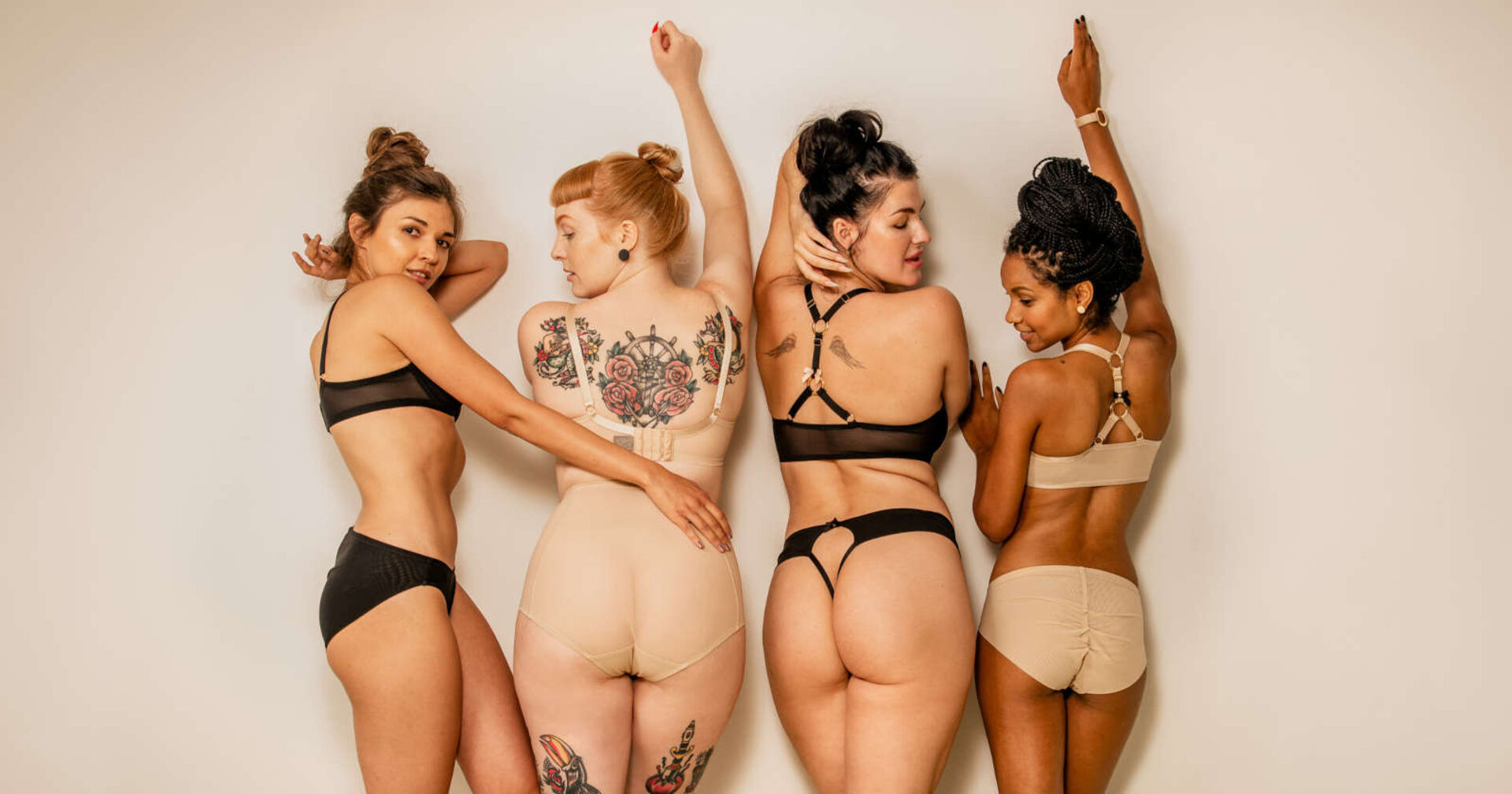 Vier Frauen stehen mit dem Oberkörper zur Wand und tragen nur Unterwäsche