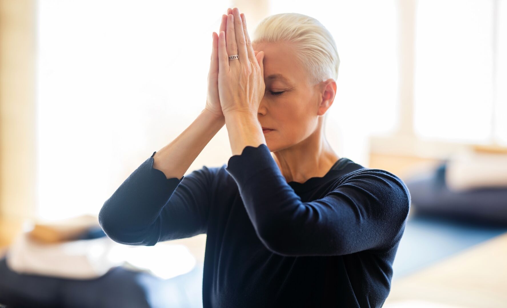 Porträt mit gefalteten Händen vor der Stirn und geschlossenen Augen