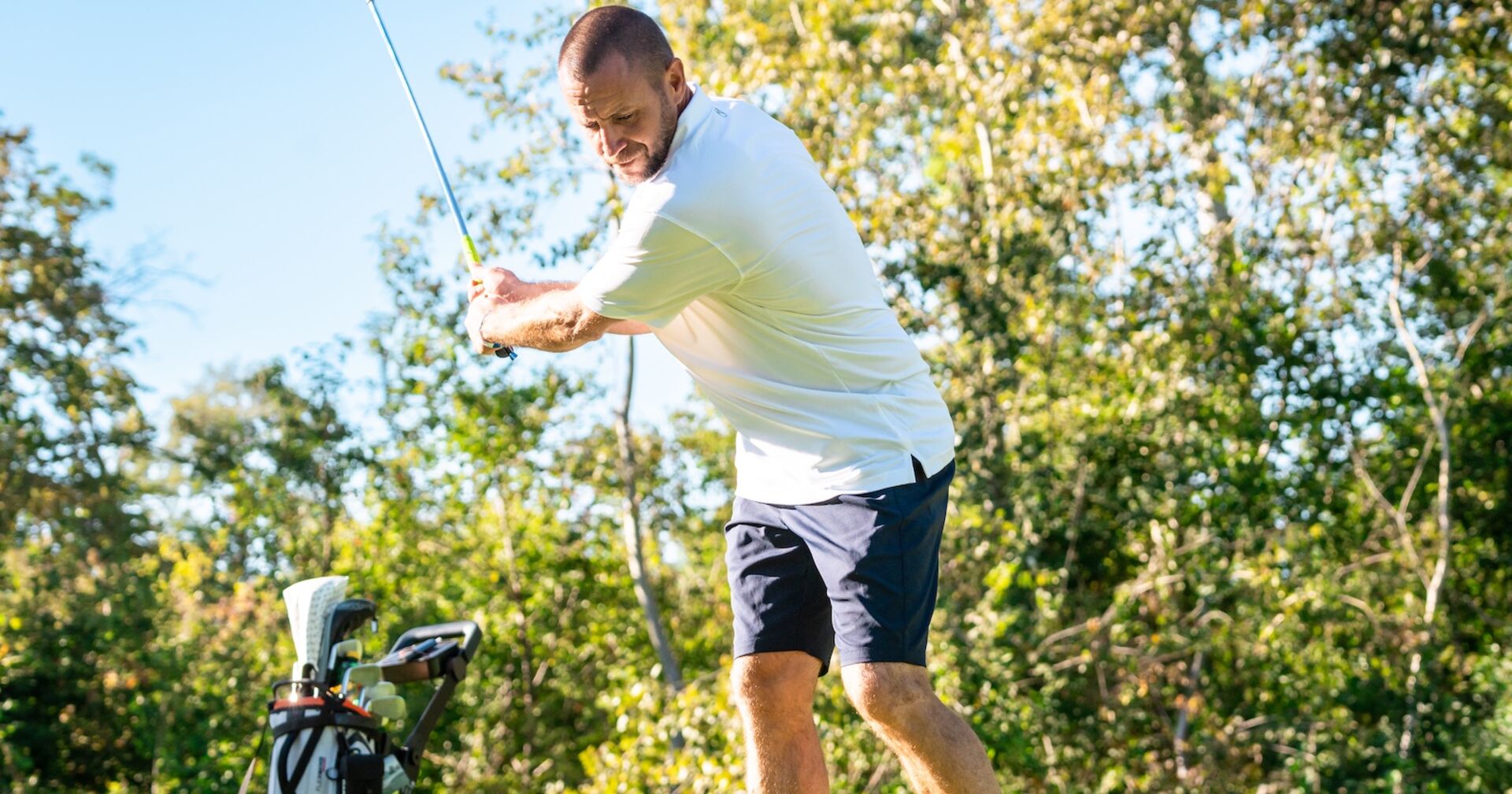 Steffen Hofmann in weißen Shirt und dunkelblauer Hose beim Abschlag am Golfplatz