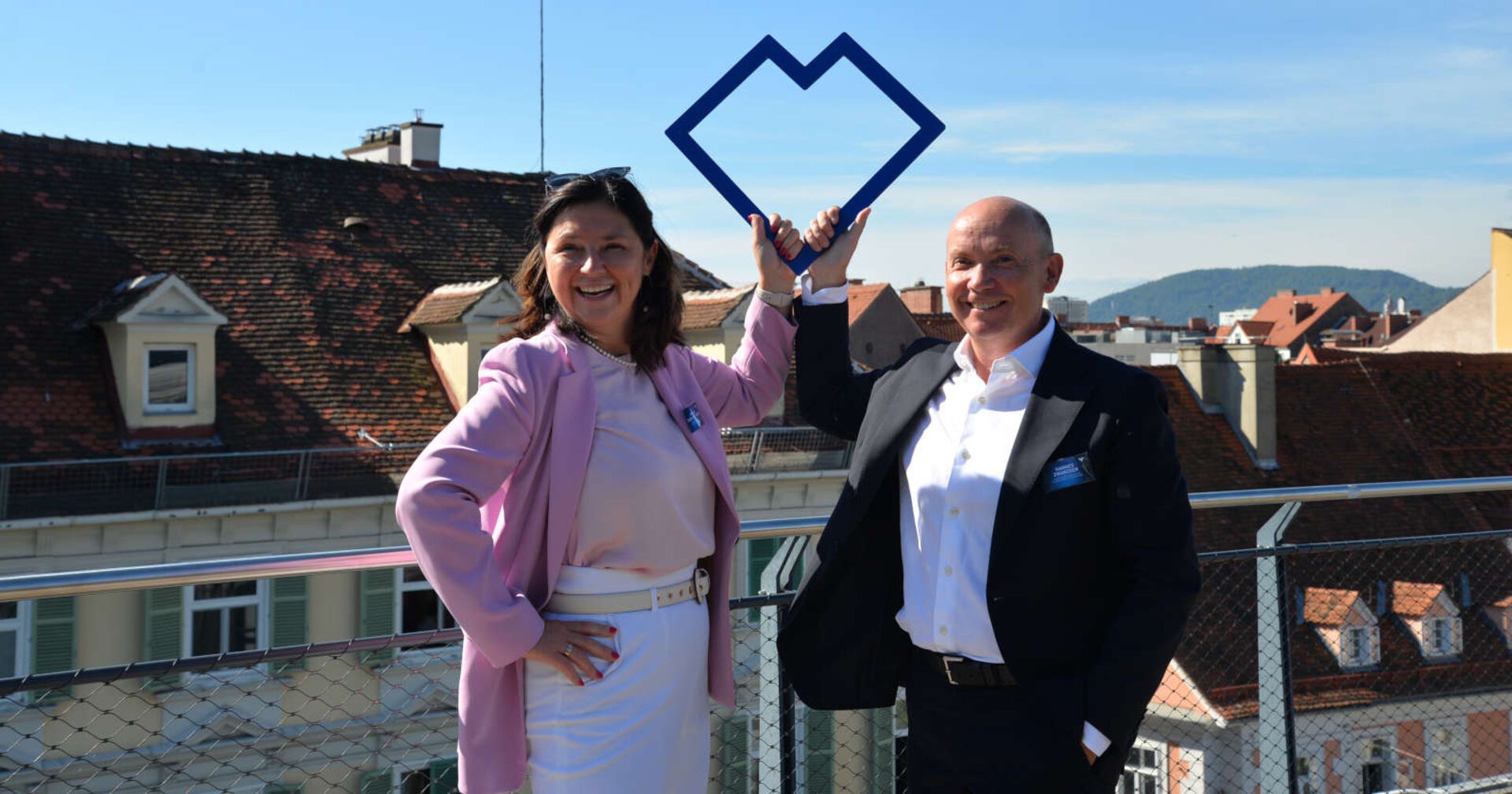 Eine Frau und ein Mann auf einer Terrasse über einer Stadt