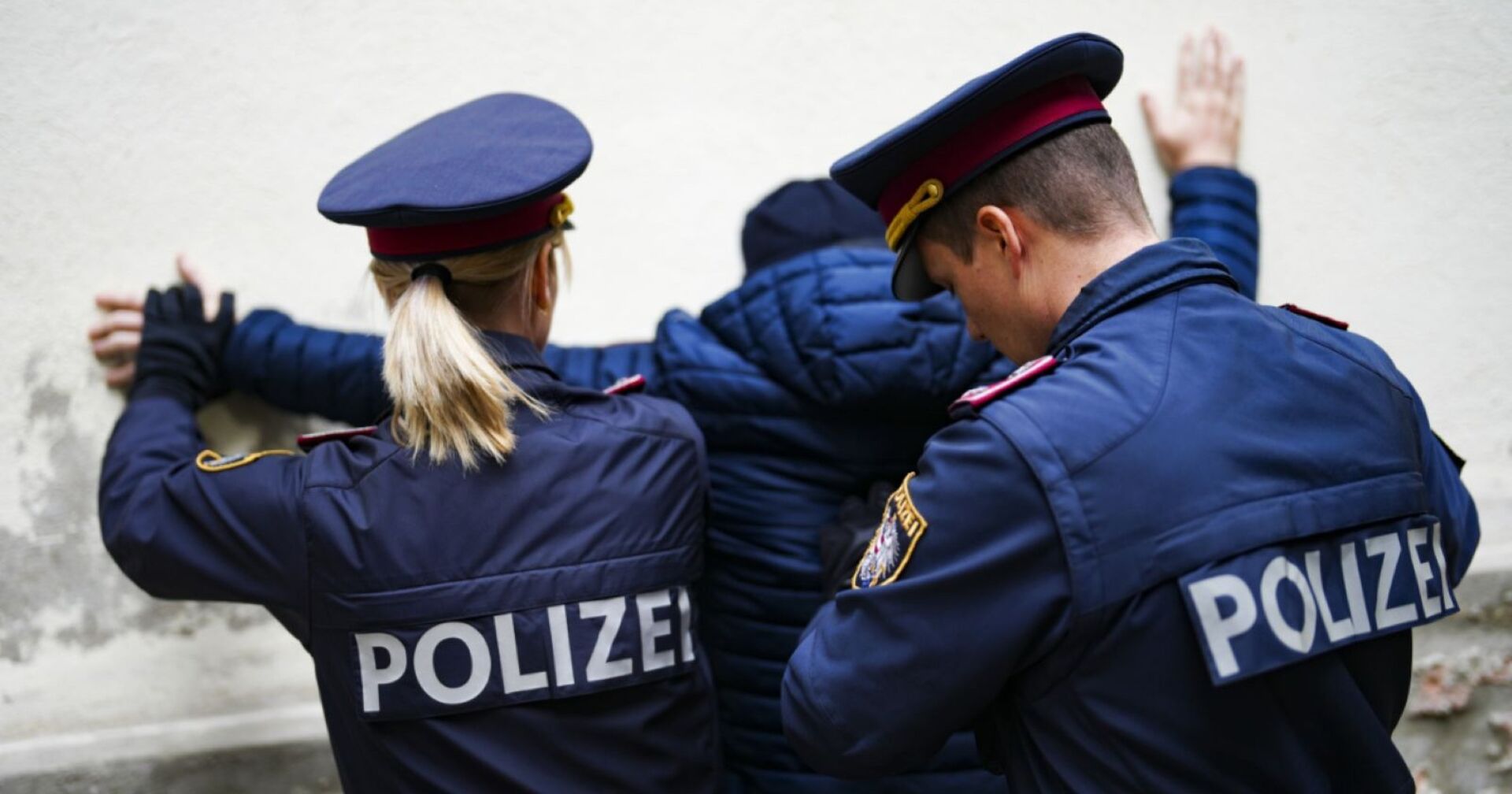 Zwei Polizisten nehmen einen Mann fest.