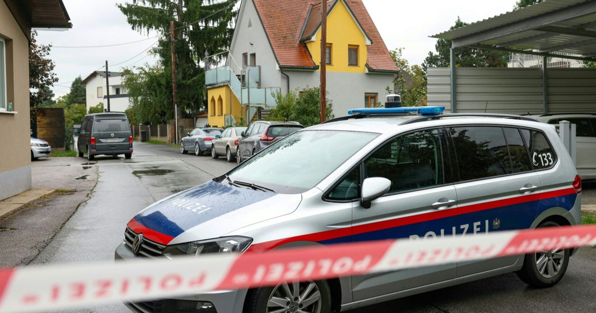 Polizeiauto mit Absperrband in einer Wohnsiedlung in Graz-Wetzelsdorf, wo ein totes Baby auf einem Carportdach gefunden wurde.