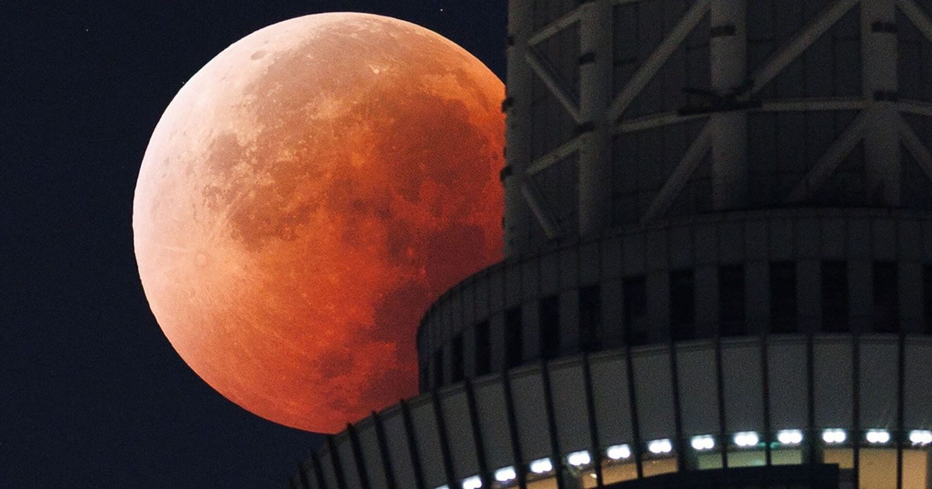 Totale Mondfinsternis 2025: Roter Blutmond hinter einem Hochhaus am Nachthimme