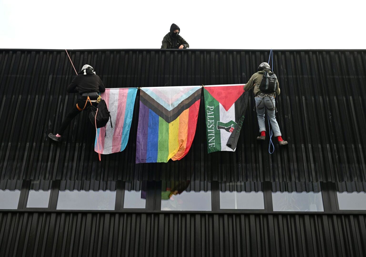 Aktivisten mit drei Fahnen am Dach des Salzburger Messezentrums.