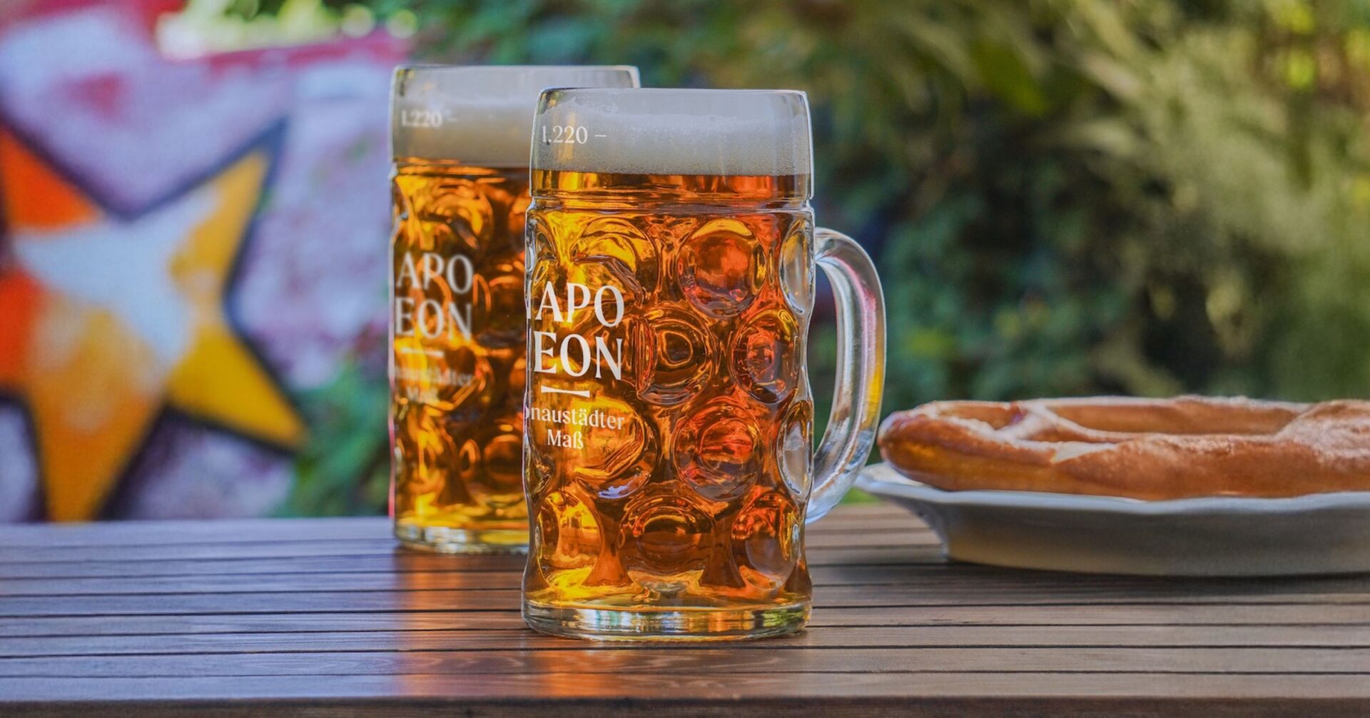 Zwei Maßkrüge mit Bier und Brezn am Holztisch