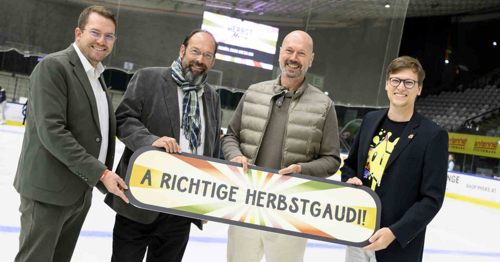 Vier Männer halten gemeinsam ein Schild hoch