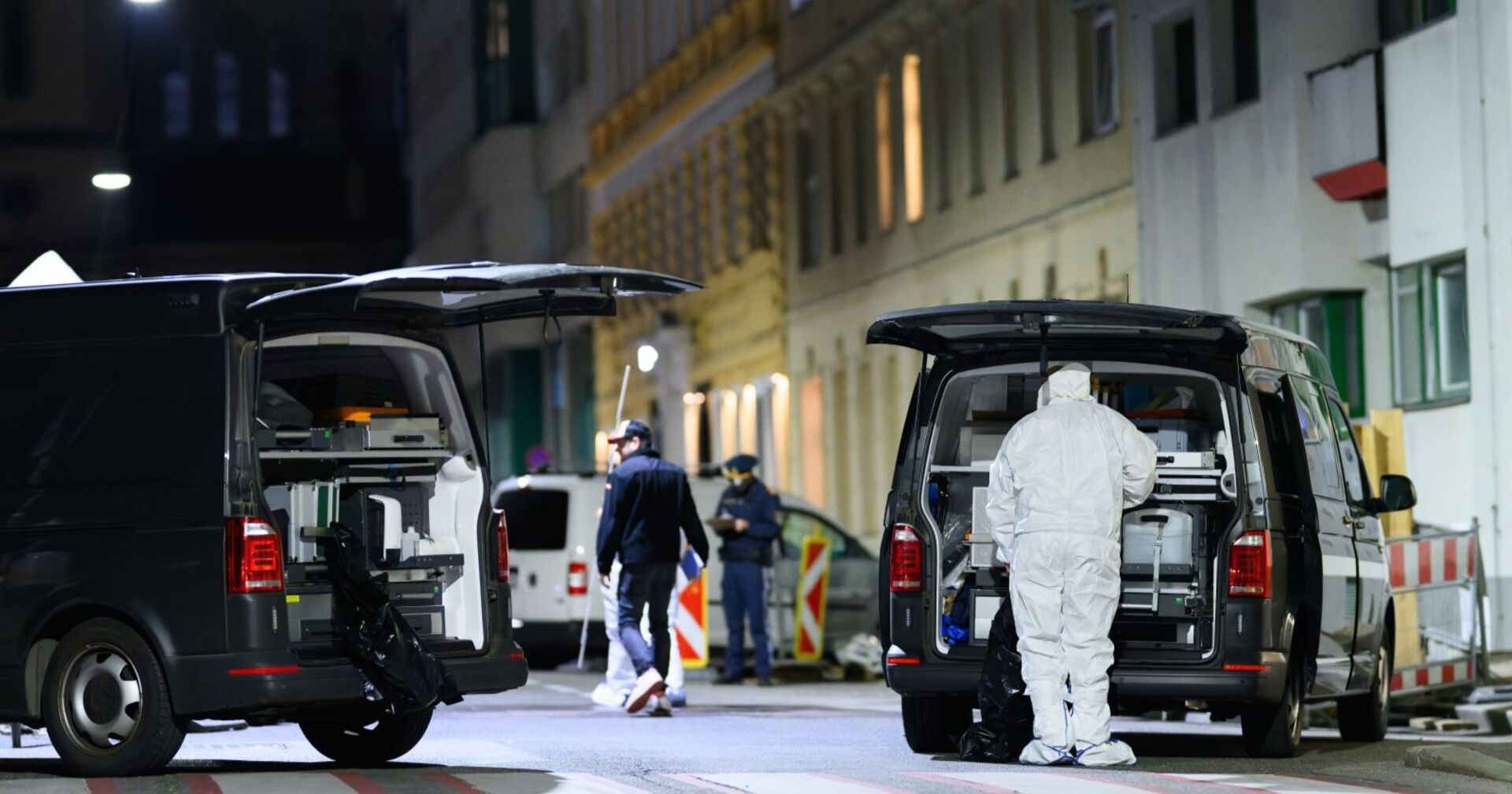 Ermittler in weißen Schutzanzügen und Polizeifahrzeuge der Spurensicherung bei der Tatortarbeit in Wien-Leopoldstadt.