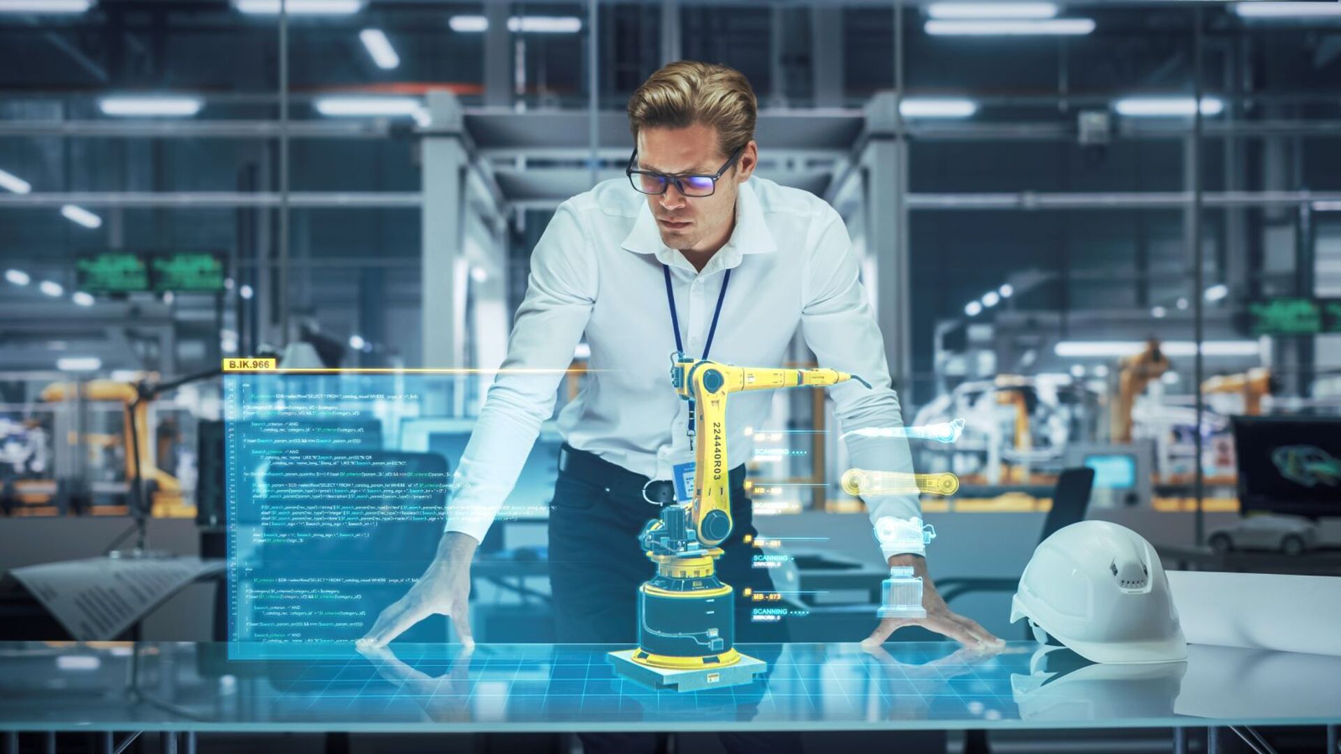 Ein Ingenieur in einem modernen Industriegebäude steht über einem Tisch und betrachtet ein holografisches 3D-Modell eines gelben Roboterarms mit eingeblendeten Programmiercodes und technischen Daten. Neben ihm liegt ein weißer Schutzhelm auf dem Tisch.