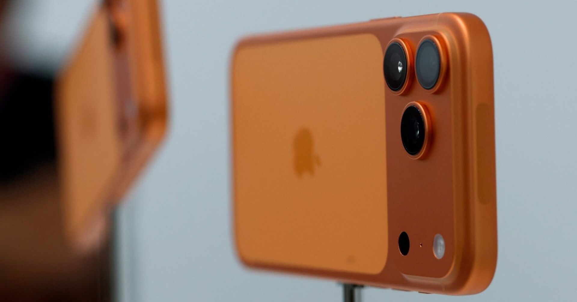 Nahaufnahme eines orangefarbenen iPhone 17 Pro mit drei Kameralinsen auf der Rückseite.