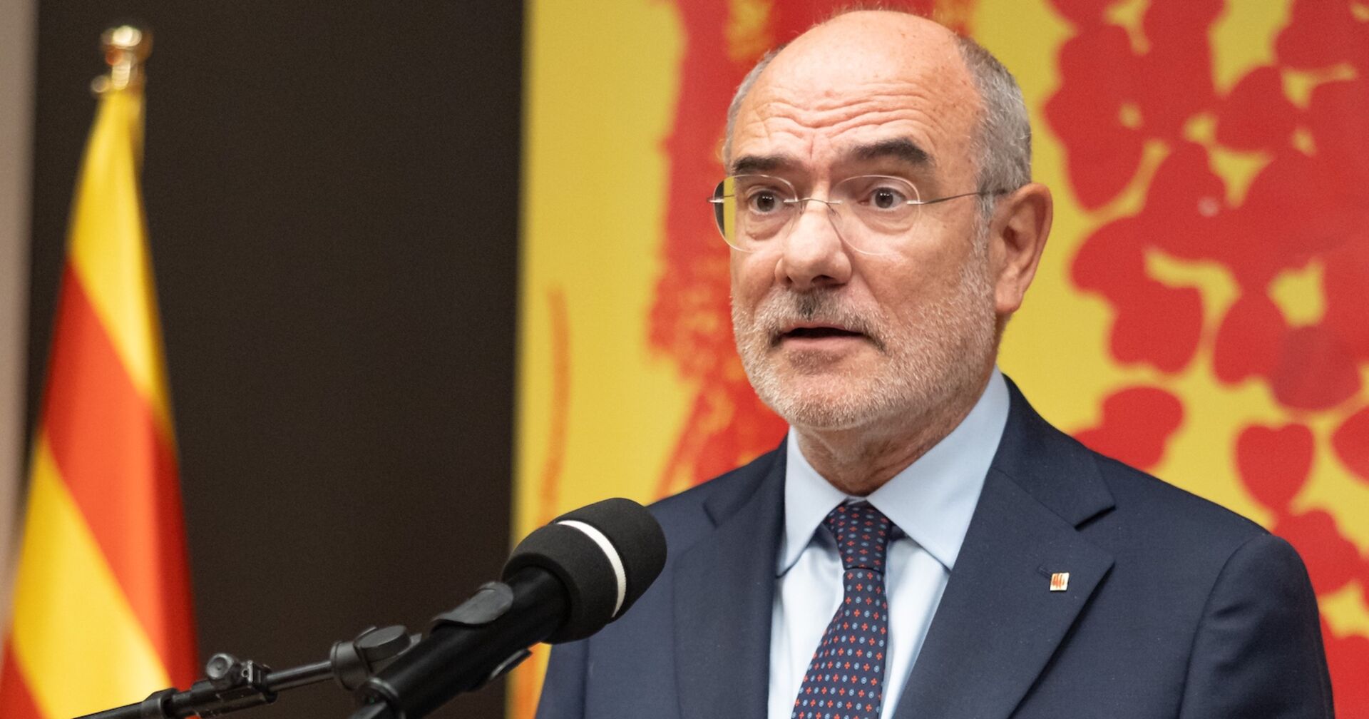 Regionalminister Jaume Duch mit Mikrophon am Podium