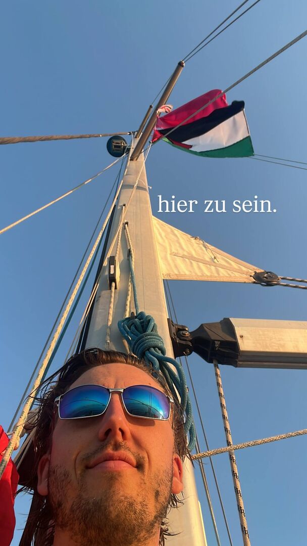 Julian Schütter auf einem Boot Richtung Gaza, hinter ihm wurde die Flaggee von Palästina auf einem Mast gehisst