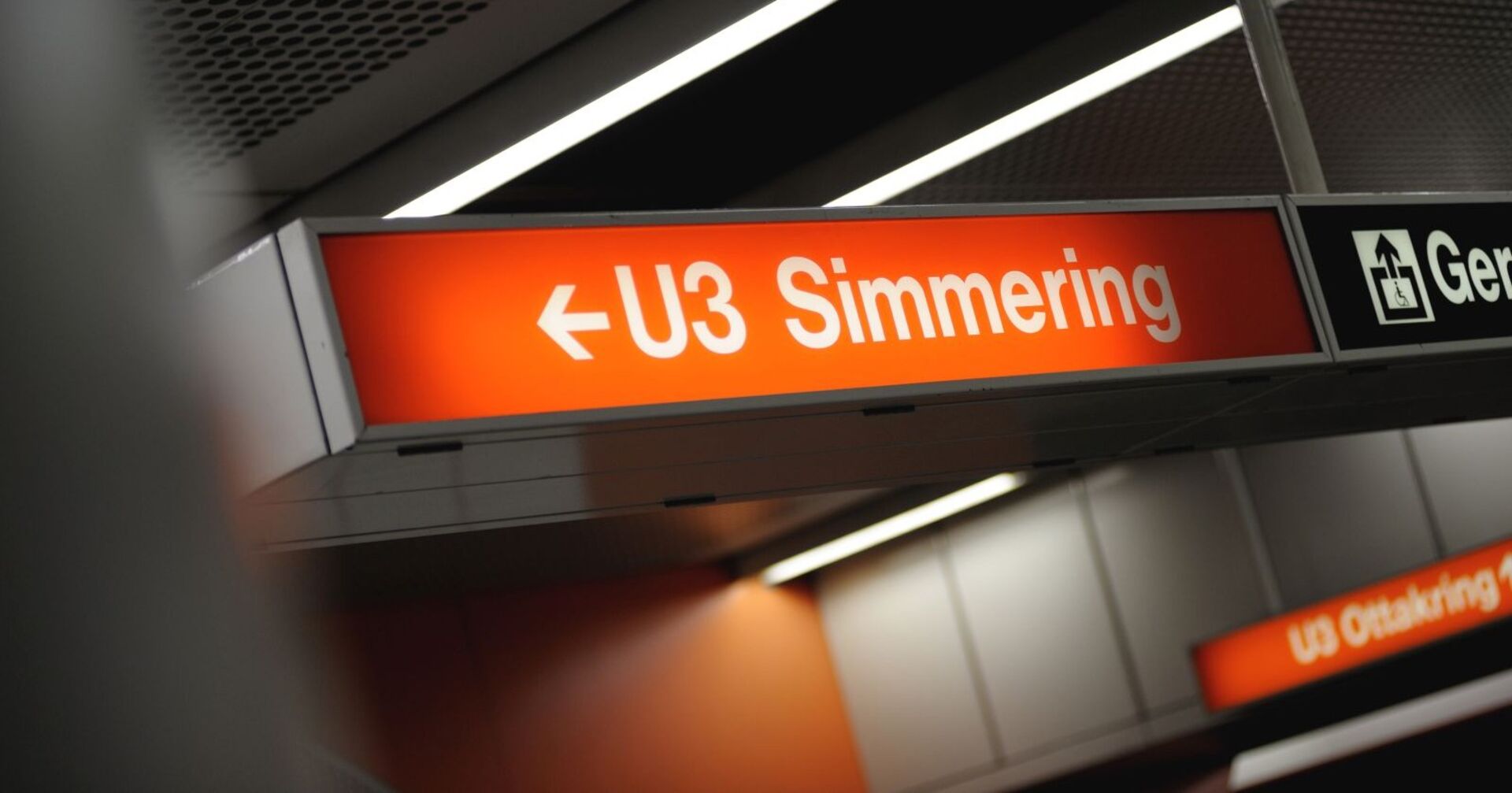 Leuchtendes Hinweisschild in einer Wiener U-Bahn-Station mit der Aufschrift „U3 Simmering“ und einem Richtungspfeil nach links. Daneben ist ein Piktogramm für einen barrierefreien Lift sichtbar.
