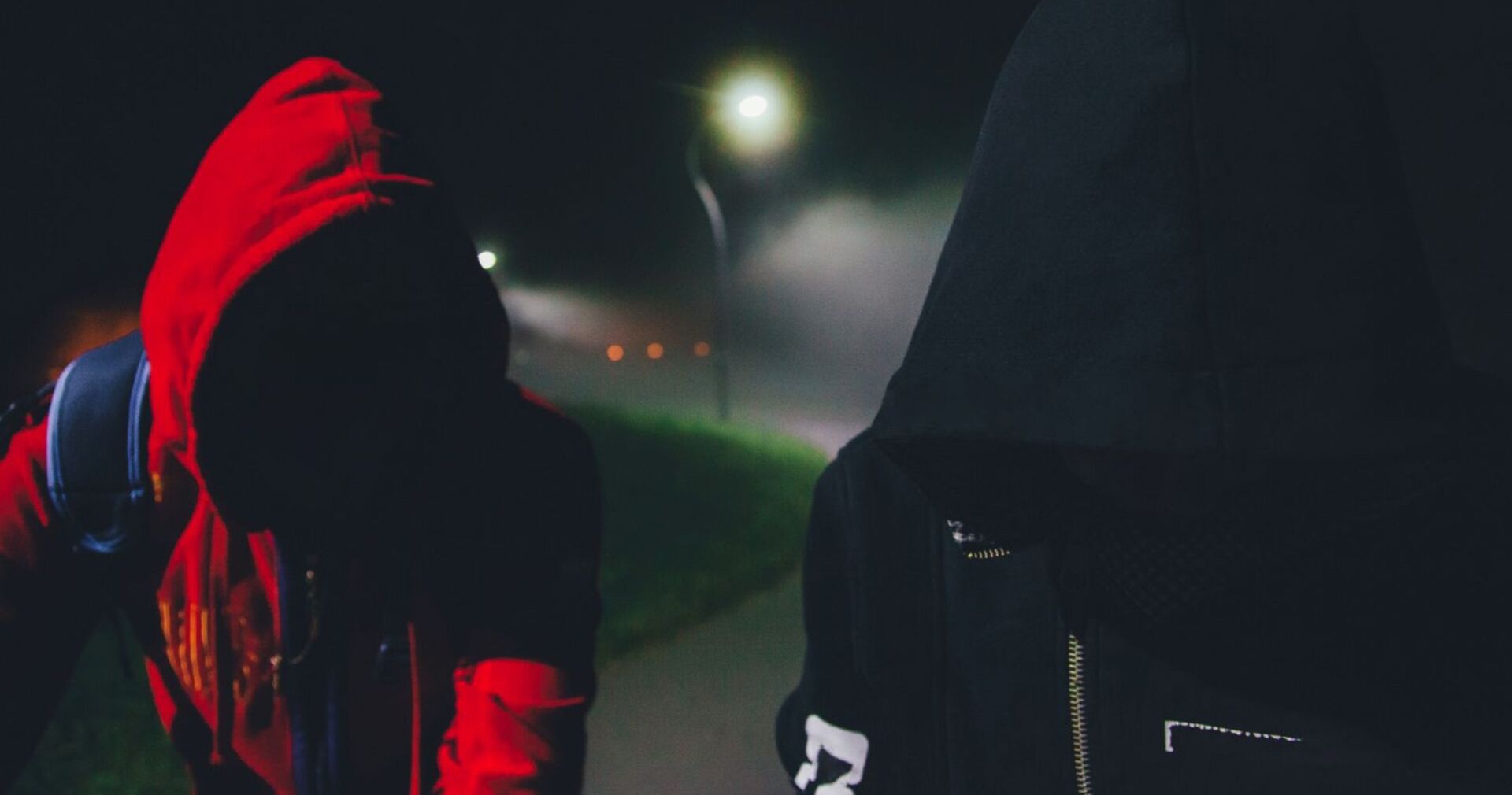 Zwei Jugendliche in der Nacht mit Kapuzenpullis.