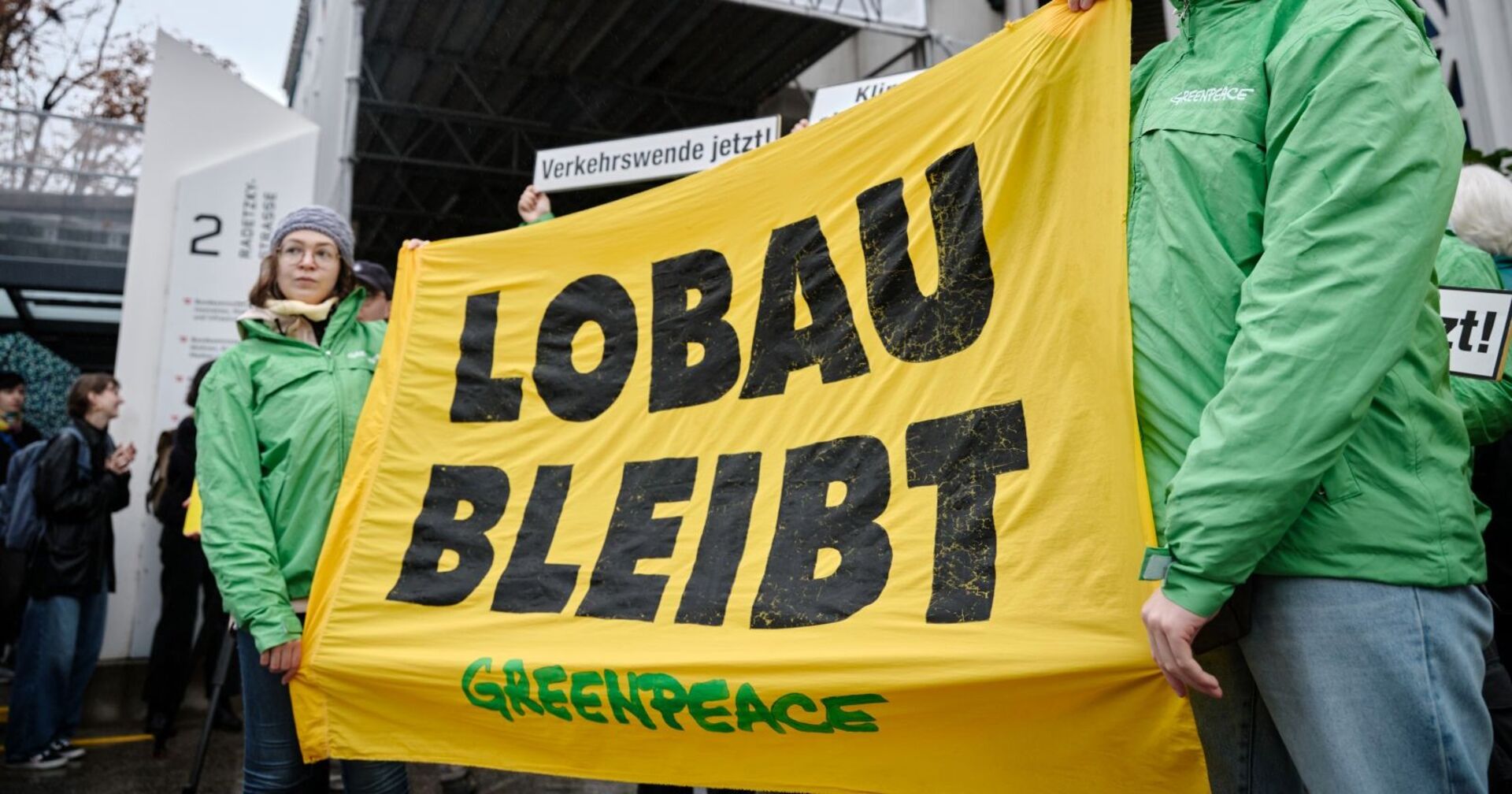 Greenpeace-aktivisten stehen vor dem Infrastrukturministerium und halten ein &quot;Lobau bleibt&quot; Transparent hoch