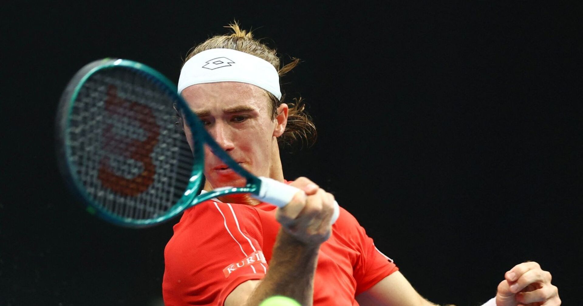 Lukas Neumayer mit rotem Shirt und Stirnband schlägt mit voller Konzentration eine Vorhand