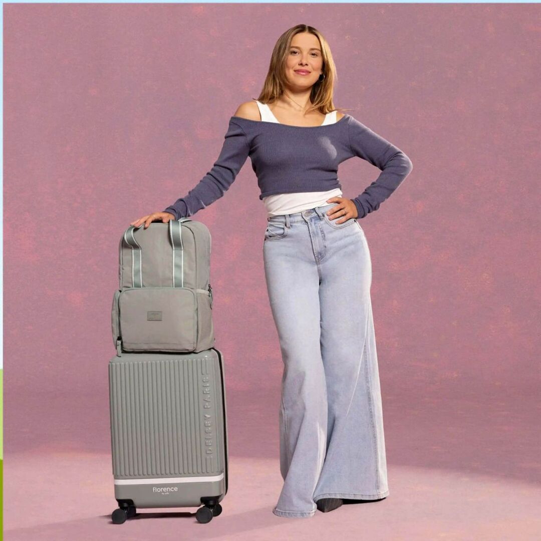 Millie Bobby Brown mit Koffer und Rucksack – die Schauspielerin zeigt, dass ihr Weg von Absagen zu internationalem Erfolg geführt hat.