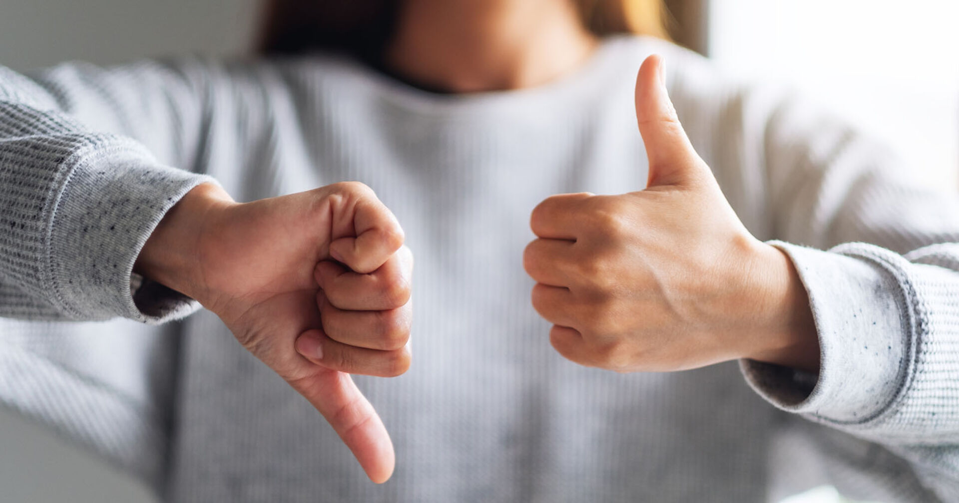 Frau zeigt einen Daumen nach unten und einen nach oben | Credit: iStock.com/Farknot_Architect