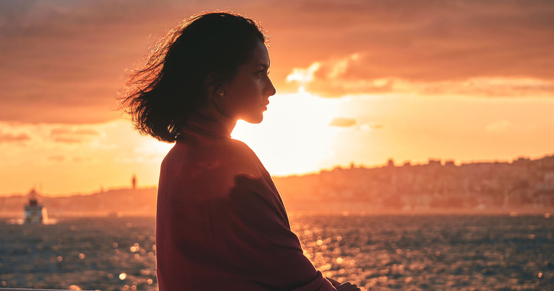 Frau steht im Sonnenuntergang | Credit: iStock.com/RomaBlack