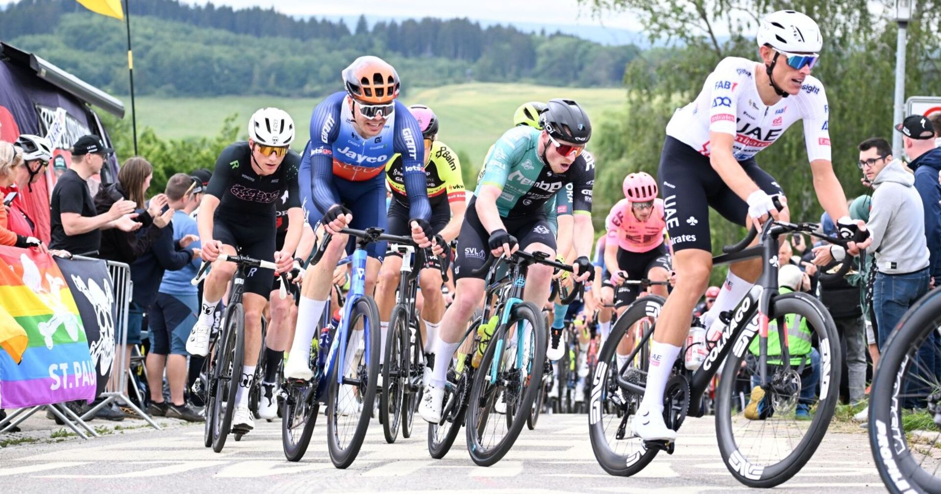Radrennfahrer kämpfen beim RiderMan in Bad Dürrheim um Positionen, Zuschauer feuern sie am Streckenrand an.