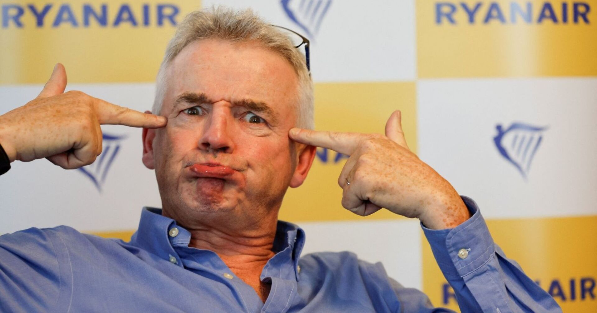 Ryanair-Chef Michael O’Leary bei einer Pressekonferenz zu den gestrichenen Maschinen am Flughafen Wien. Er zieht Grimassen und zeigt auf sein Gesicht.