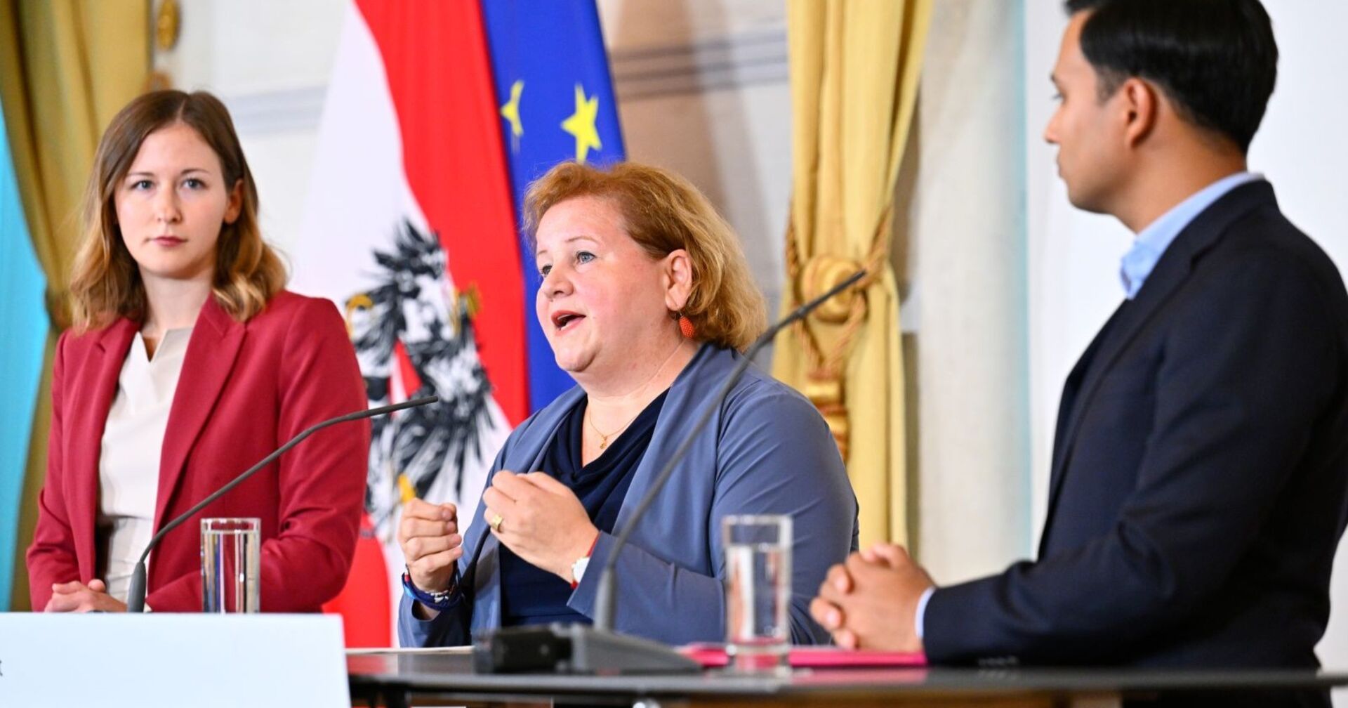 Integrationsministerin Claudia Plakolm (ÖVP), Sozialministerin Korinna Schumann (SPÖ) und NEOS-Klubobmann Yannick Shetty präsentierten im Bundeskanzleramt die Eckpunkte der „Sozialhilfe NEU“. Im Hintergrund die österreichische und die EU-Flagge.