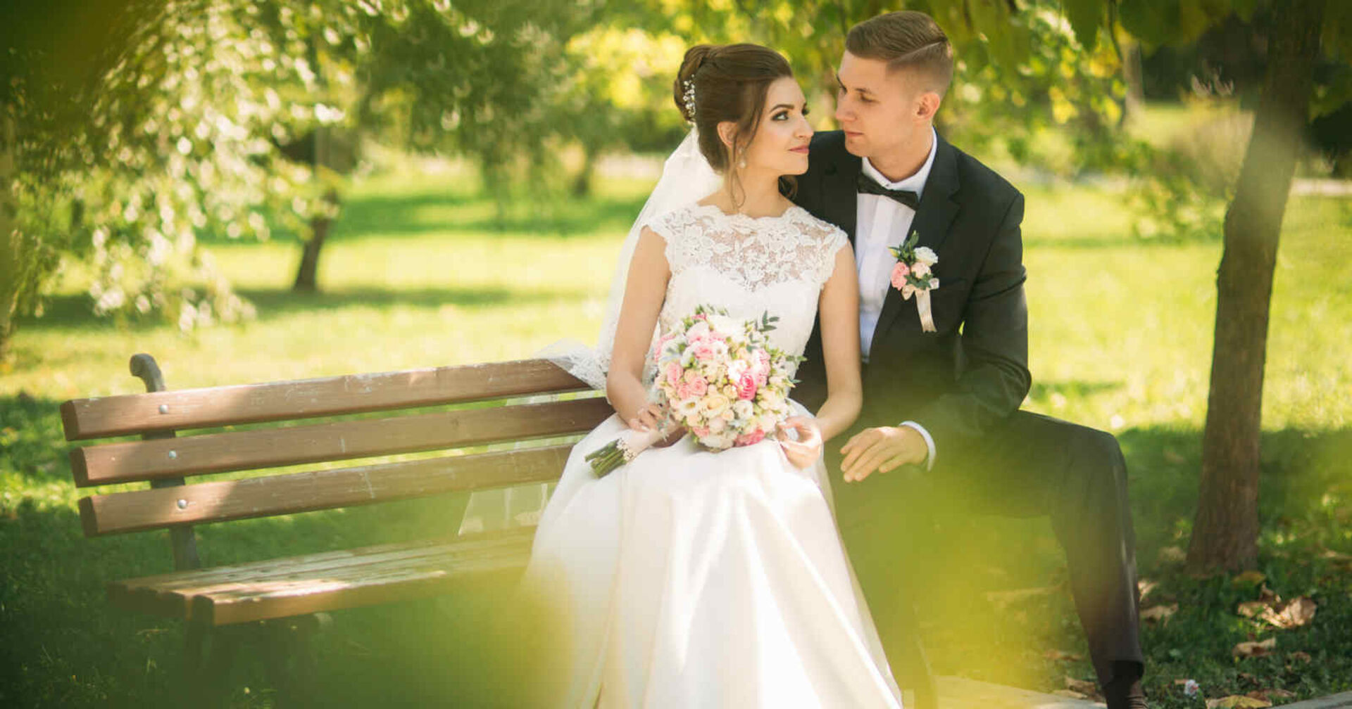 Braut und Bräutigam sitzen auf einer Parkbank
