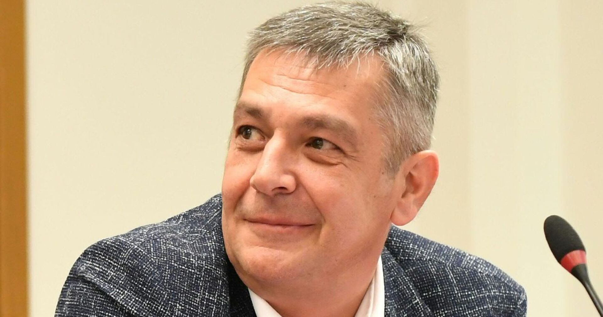 Porträt von Wolfgang Seidl, FPÖ-Politiker aus Wien, lächelnd vor einem Mikrofon.