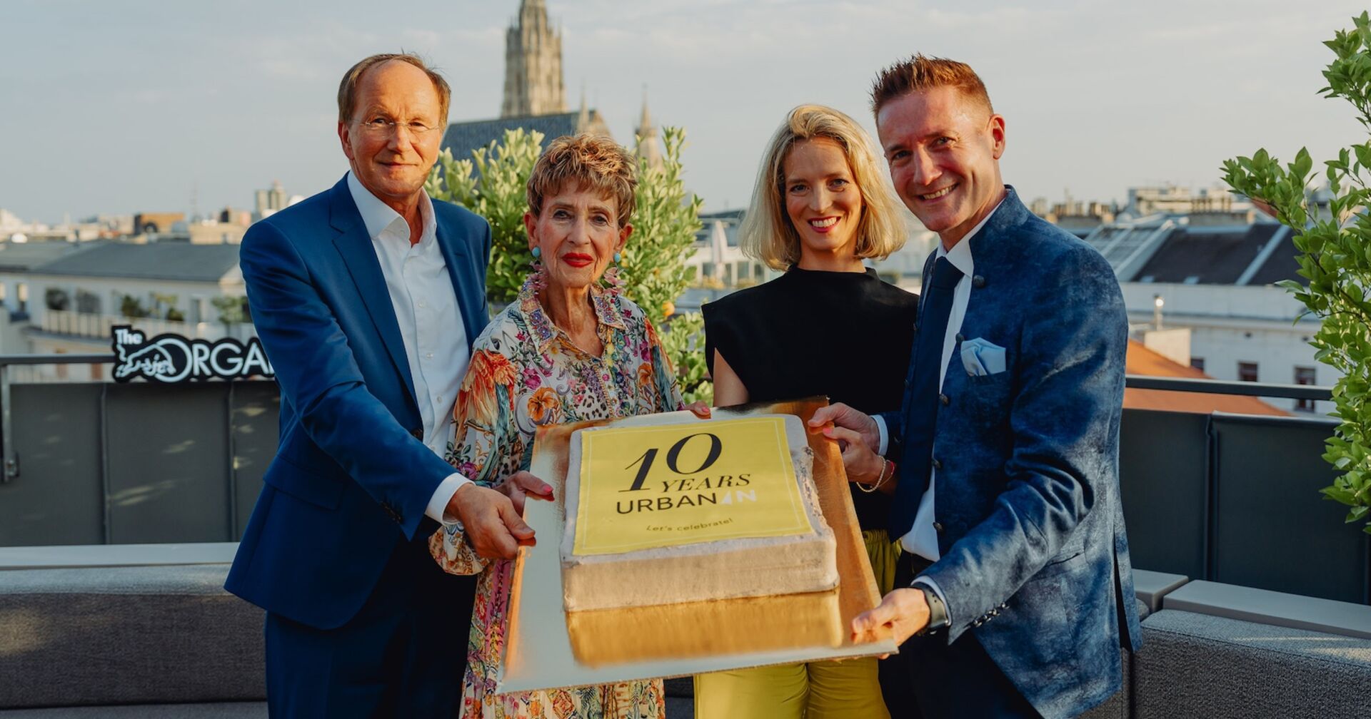 Quartett mit Jubiläumstorte auf einer Dachterrasse mit Blick auf den Stephansdom