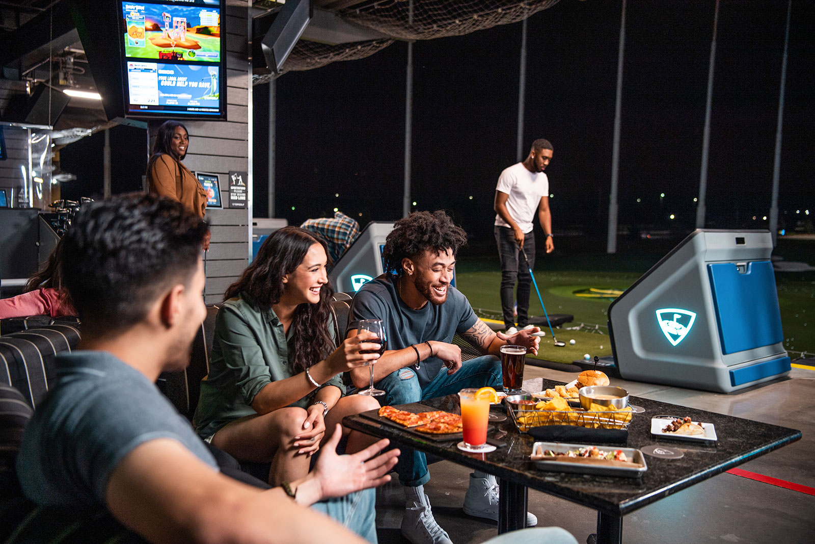 Gesellige Runde sitzt um einen Tisch im Lokal | Credit: Topgolf Wien