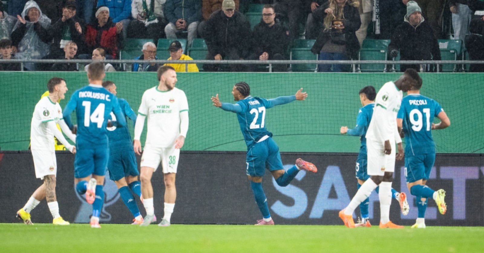 Rapid-Wien-Spieler in weißen Trikots und Fiorentina-Spieler in blauen Trikots während eines Conference-League-Spiels, Fiorentina feiert ein Tor.