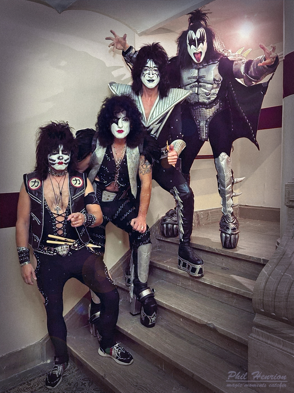 Vier Musiker der KISS Forever Band in originalgetreuen Kostümen und Schminke posieren auf einer Treppe vor ihrem Auftritt.