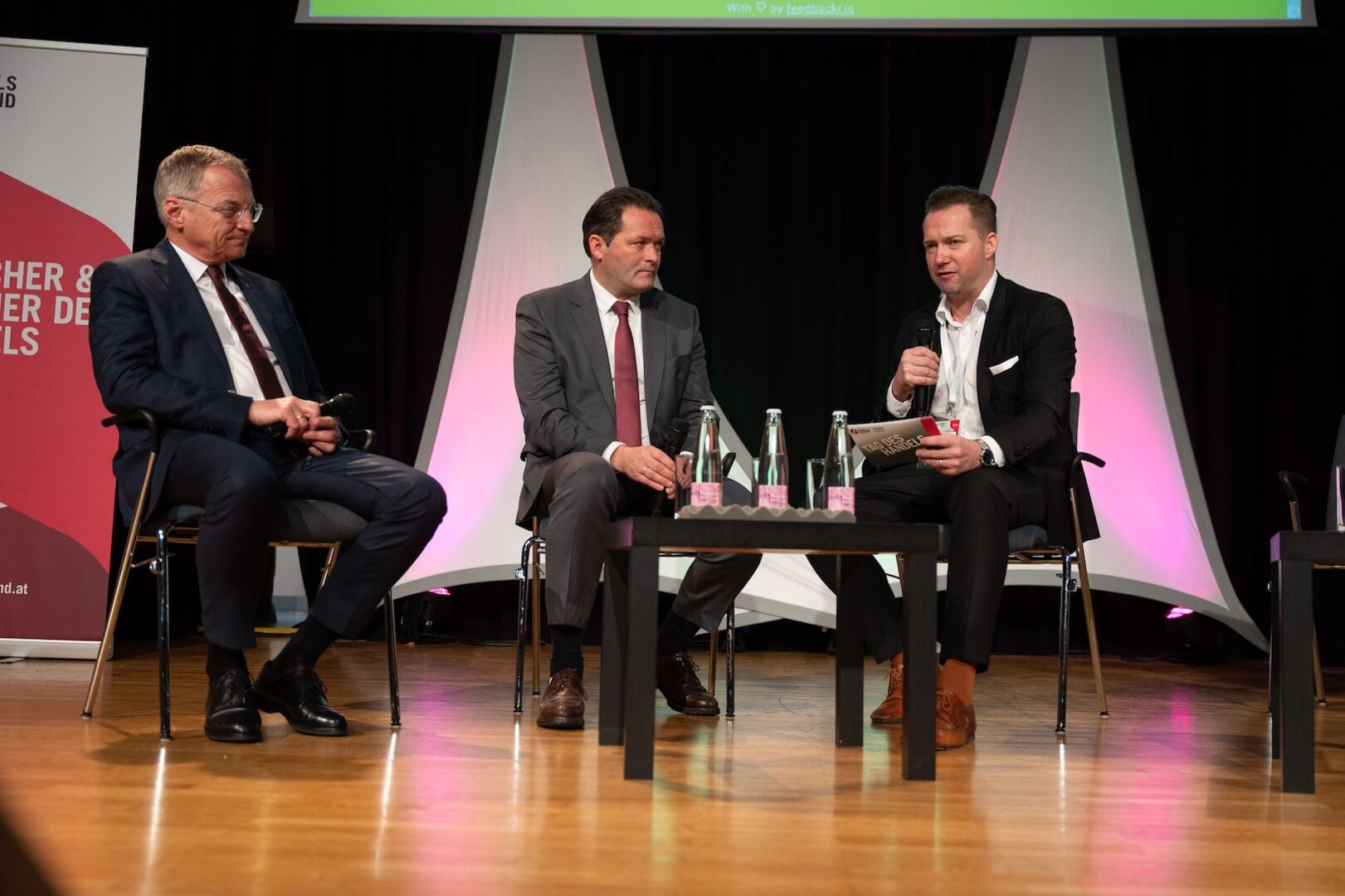 Auf einer Bühne nebeneinander sitzend