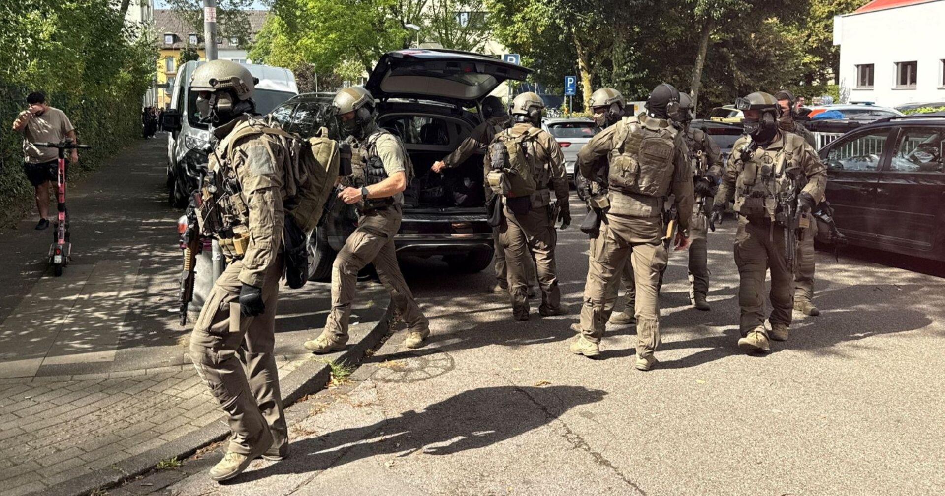 Mehrere schwer bewaffnete Polizisten in Schutzkleidung stehen bei einem Einsatzfahrzeug während eines Großeinsatzes der Polizei in Essen.