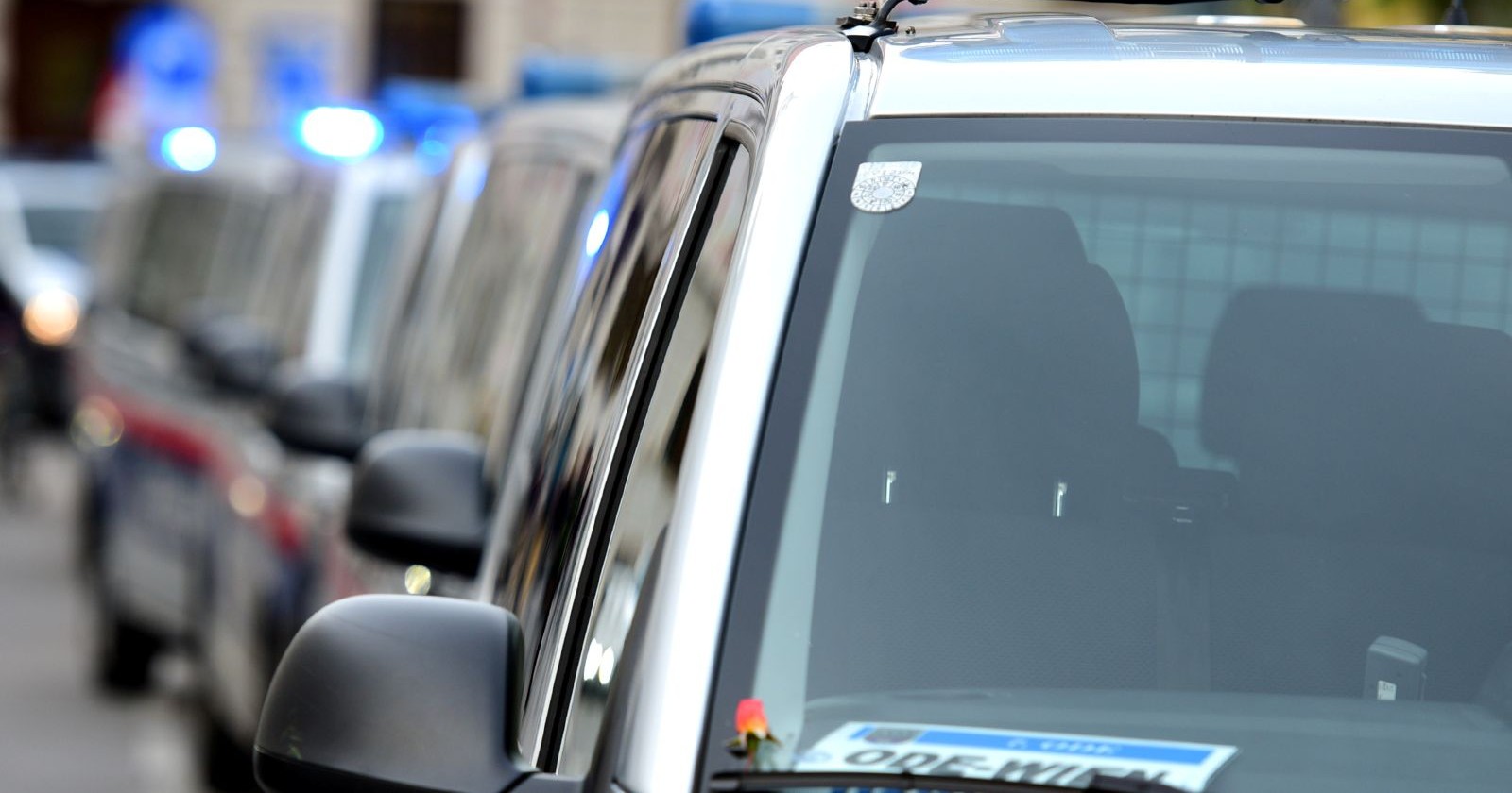 Reihe österreichischer Polizeiautos mit eingeschaltetem Blaulicht in einer Grazer Straße.