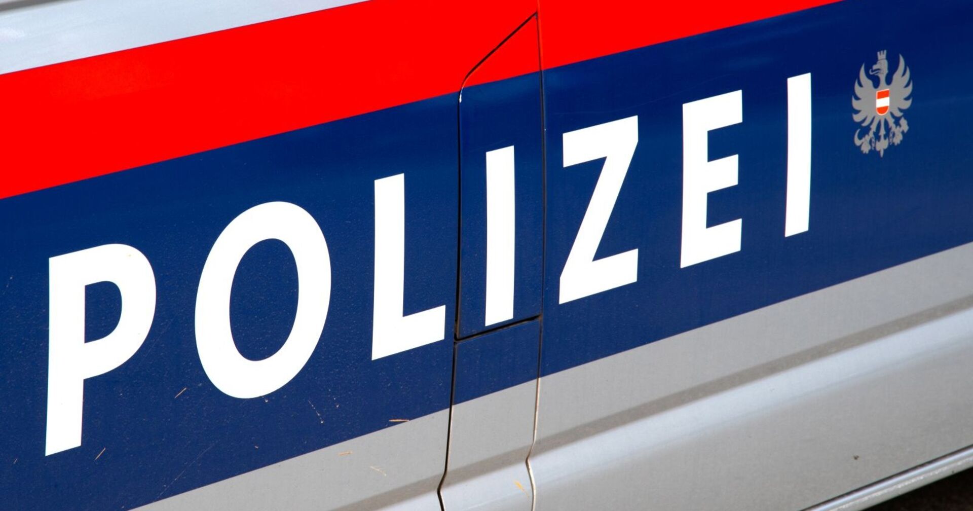 Foto einer Seite eines Polizeiwagens auf dem der österreichische Polizeischriftzug neben dem Bundesadler prangt