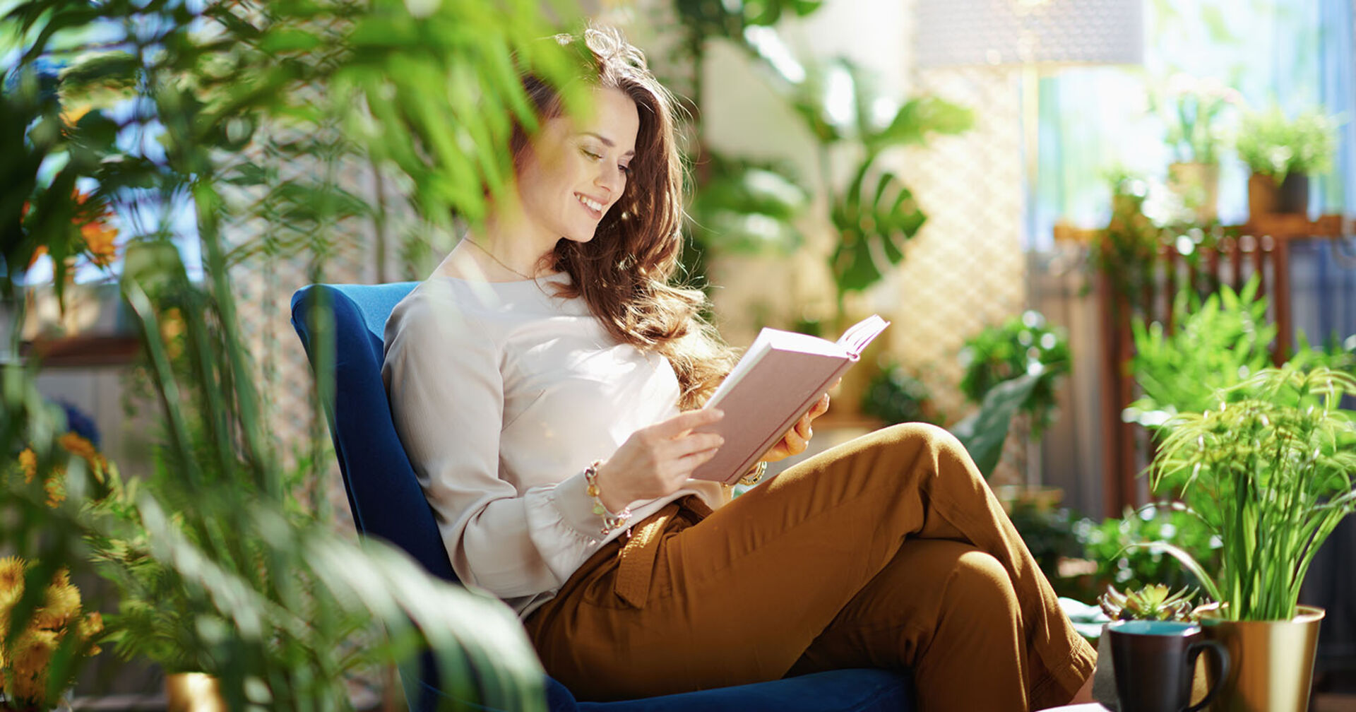 Frau sitzt in der Mitte von Pflanzen | Credit: iStock.com/CentralITAlliance