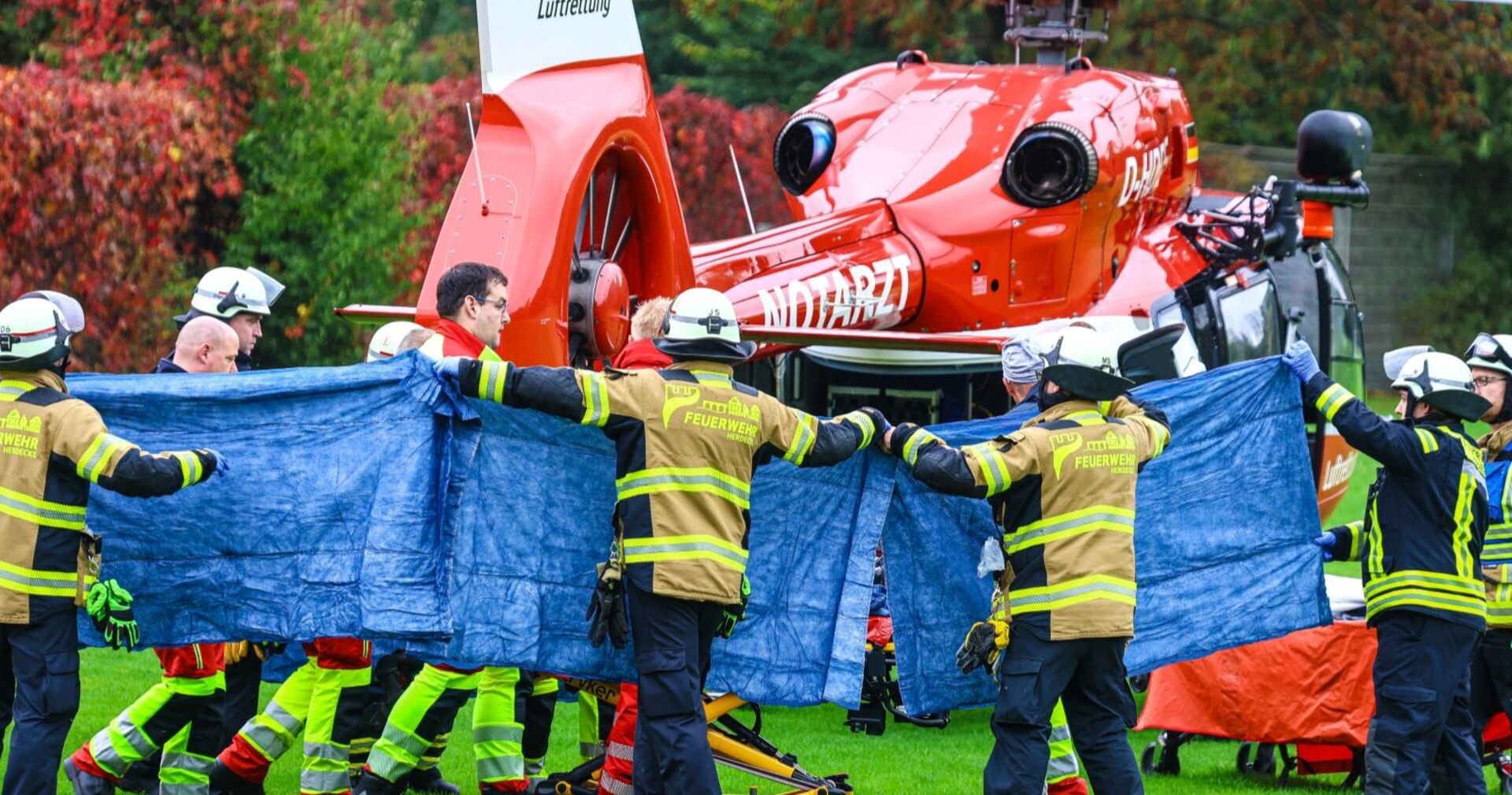 Feuerwehrleute und Sanitäter in Herdecke transportieren die schwerverletzte Iris Stalzer unter Sichtschutz zu einem Rettungshubschrauber nach einem Gewaltverbrechen.