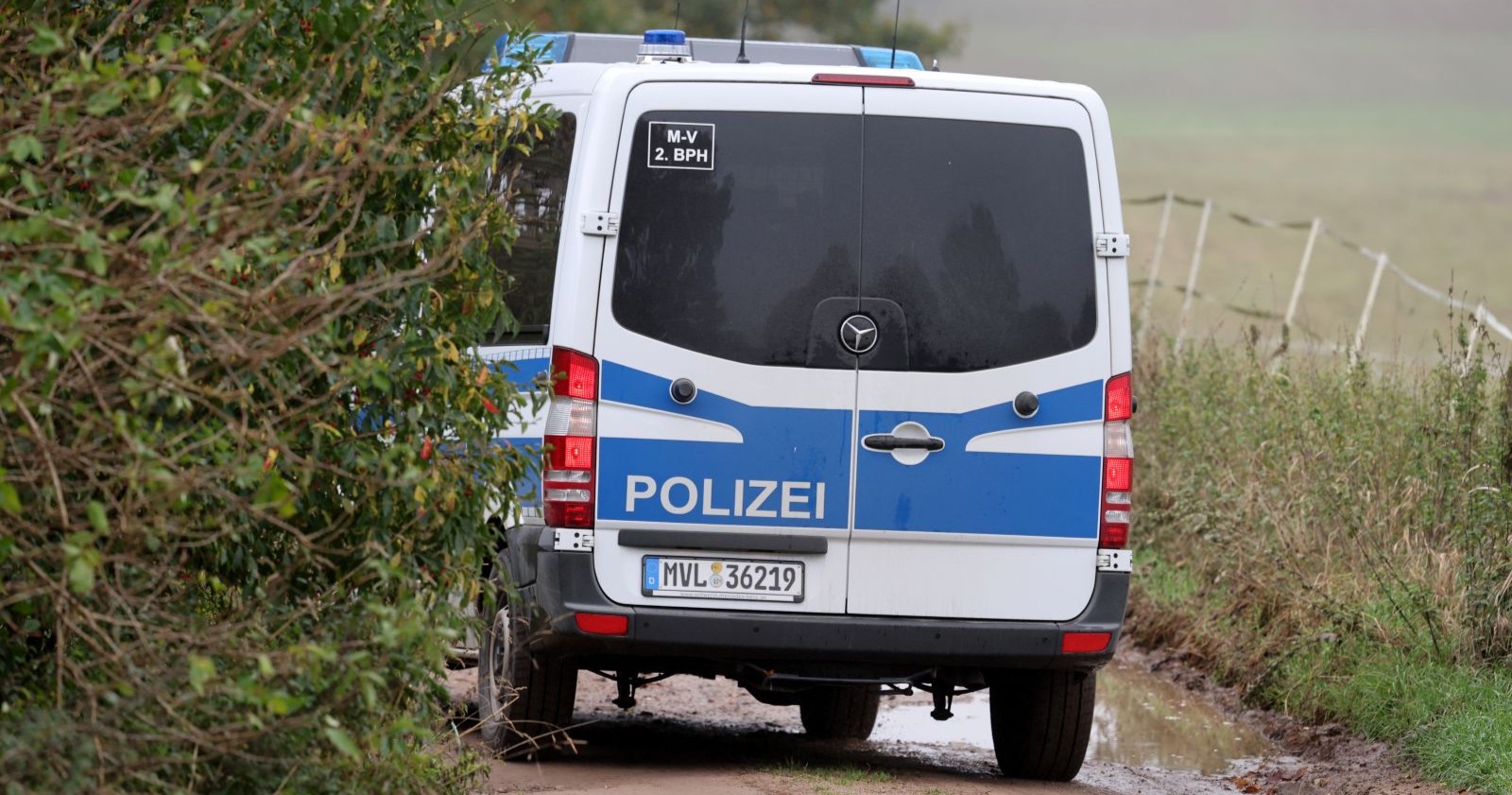 Polizeiwagen auf einem schlammigen Feldweg bei Klein Upahl, wo Ermittler nach dem Fund des toten Fabian Spuren sichern.