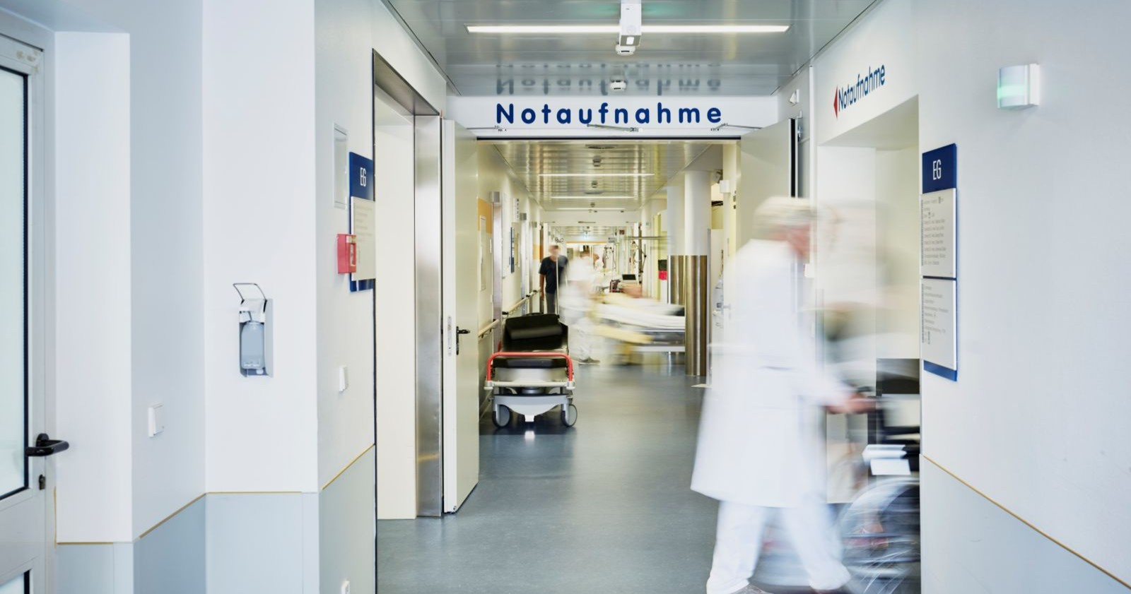 Notaufnahme eines Krankenhauses mit medizinischem Personal und Tragen auf einem Flur, aufgenommen in einer österreichischen Klinik.