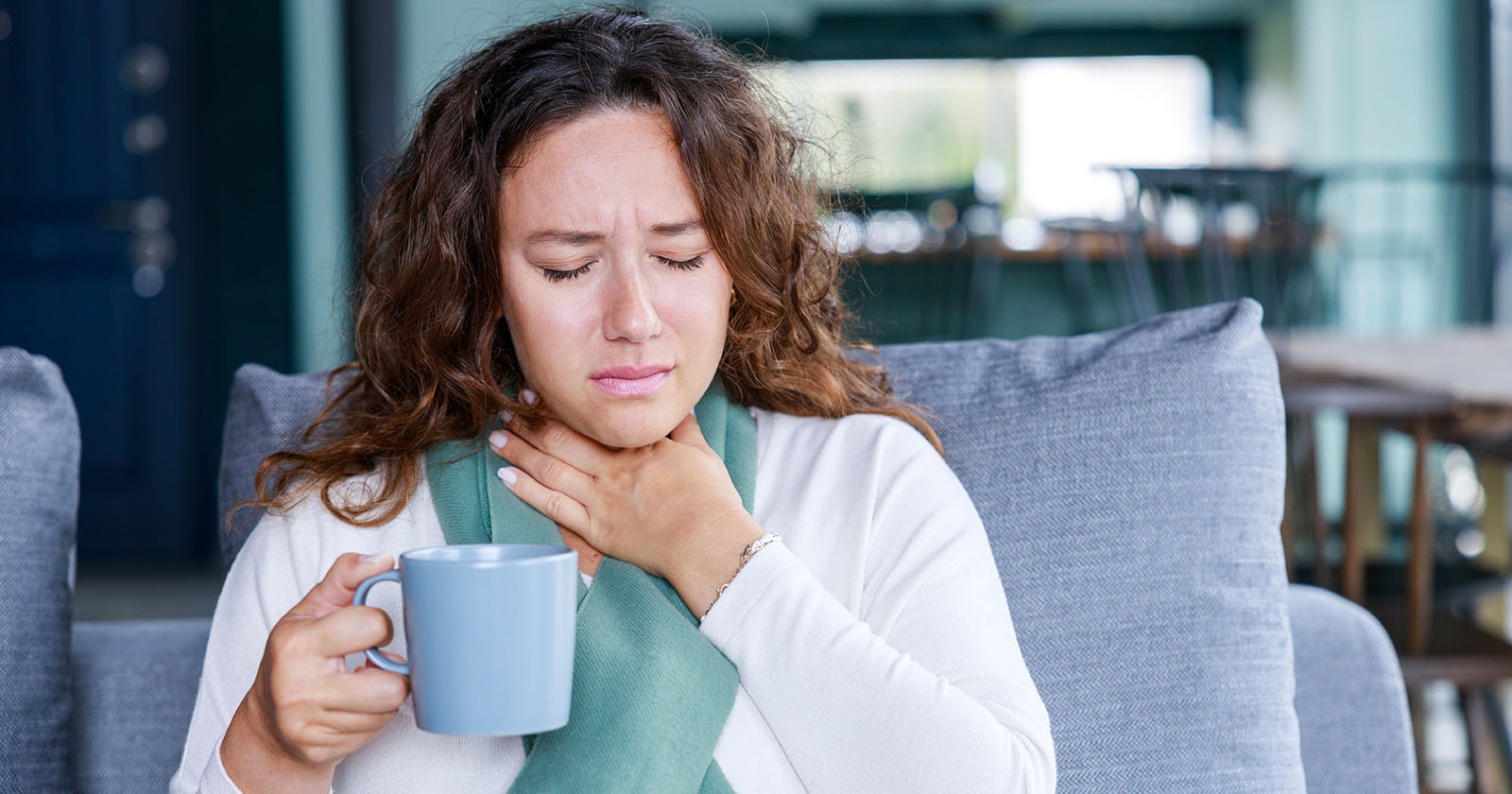 Frau greift sich an Hals | Credit: iStock.com/eternalcreative
