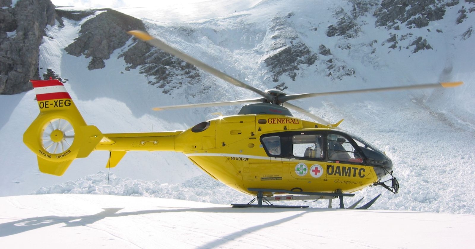 ÖAMTC-Notarzthubschrauber landet im verschneiten Hochgebirge während eines Rettungseinsatzes.