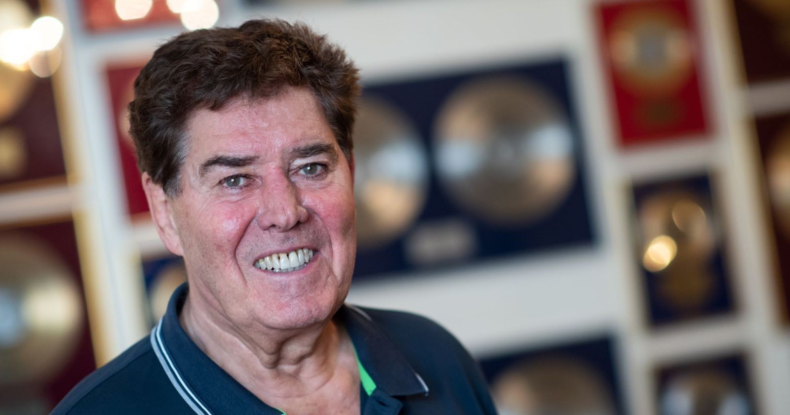 Jack White steht lächelnd vor einer Wand mit Gold- und Platinplatten in seinem Berliner Studio.