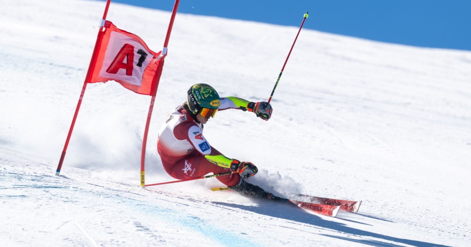 Eine Skirennläuferin legt sich beim Riesentorlauf in Sölden dynamisch in die Kurve und passiert präzise das rote Tor auf der Gletscherpiste.