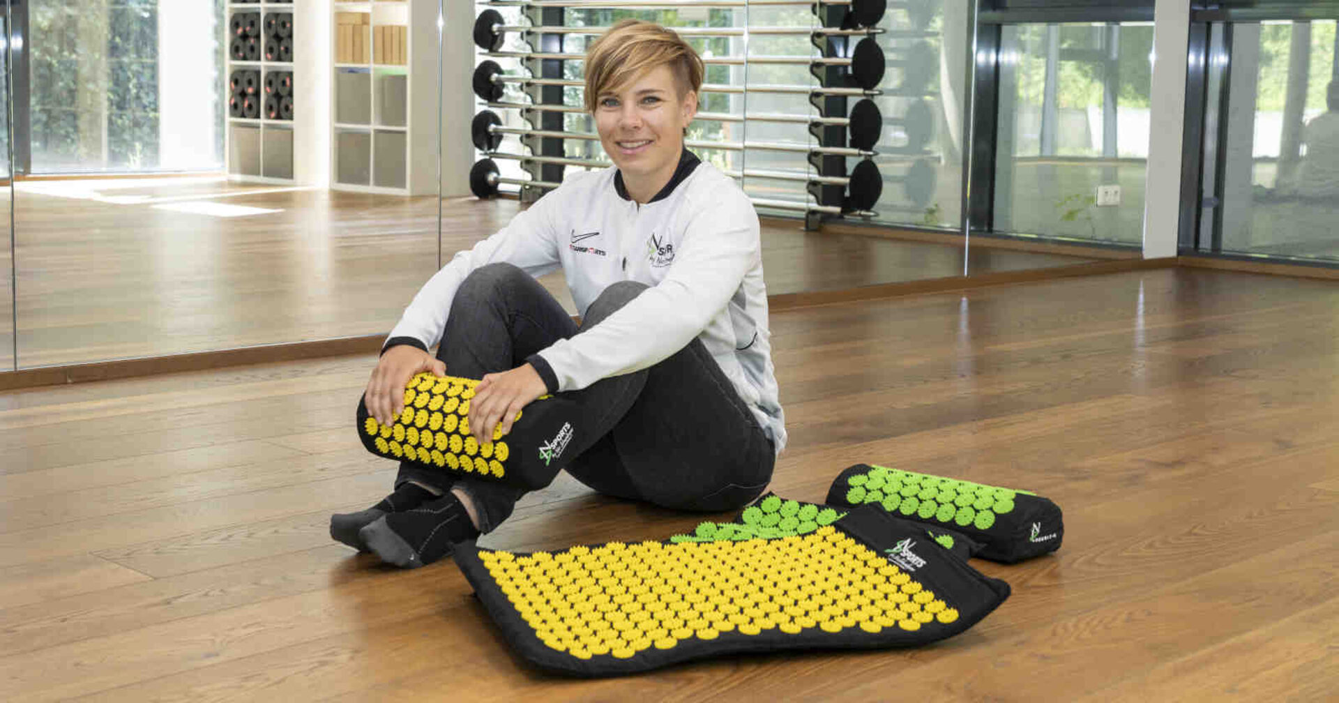 Eine blondhaarige Frau sitzt vor zwei Matten