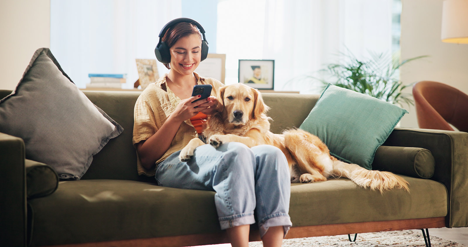 Frau sitzt mit Hund auf Sofa und hört einen Podcast | Credit: iStock.com/Jacob Wackerhausen