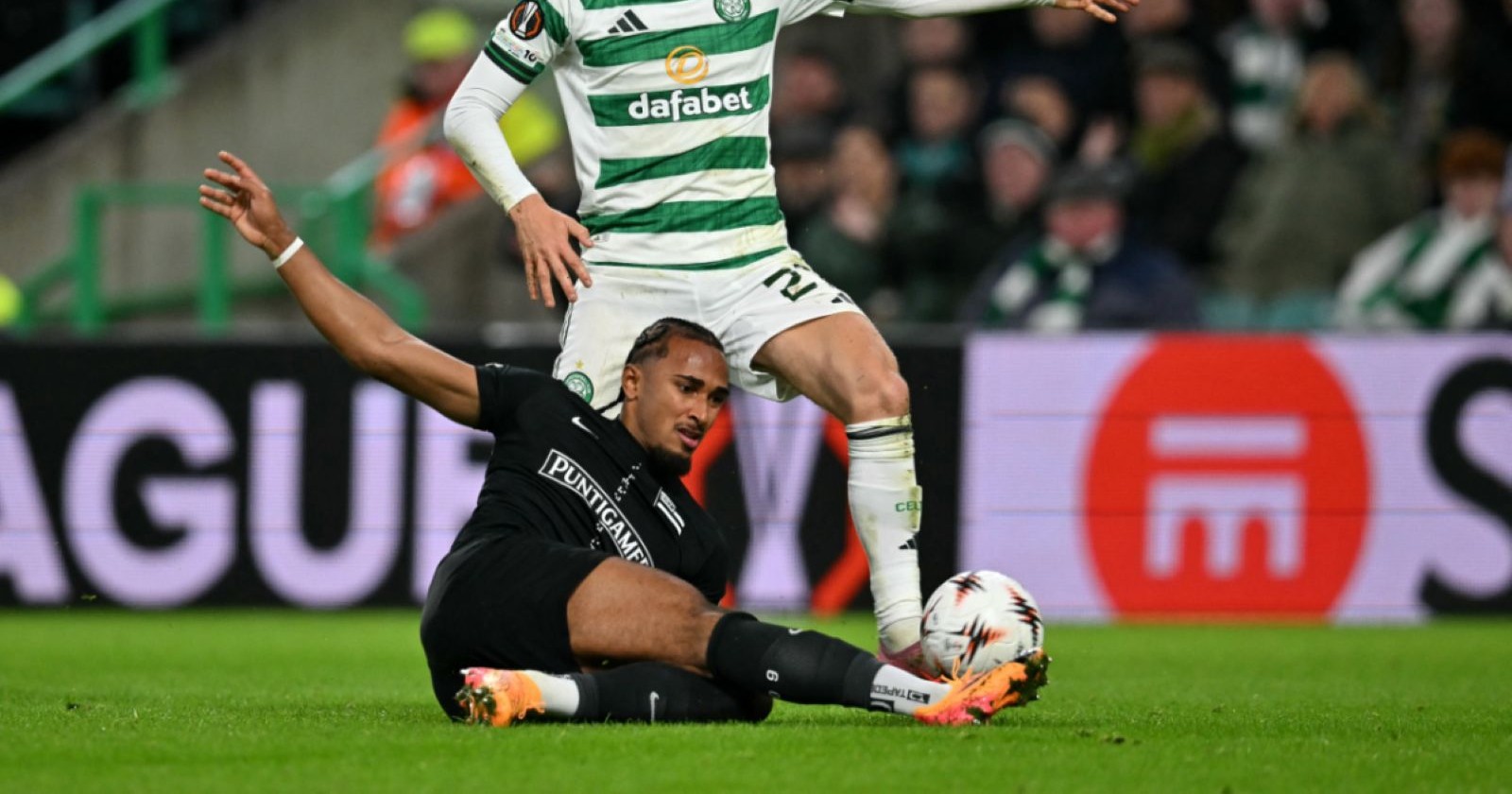 Sturm-Graz-Spieler im schwarzen Trikot grätscht im Zweikampf gegen einen Celtic-Glasgow-Spieler im grünen Trikot während eines Europa-League-Spiels.