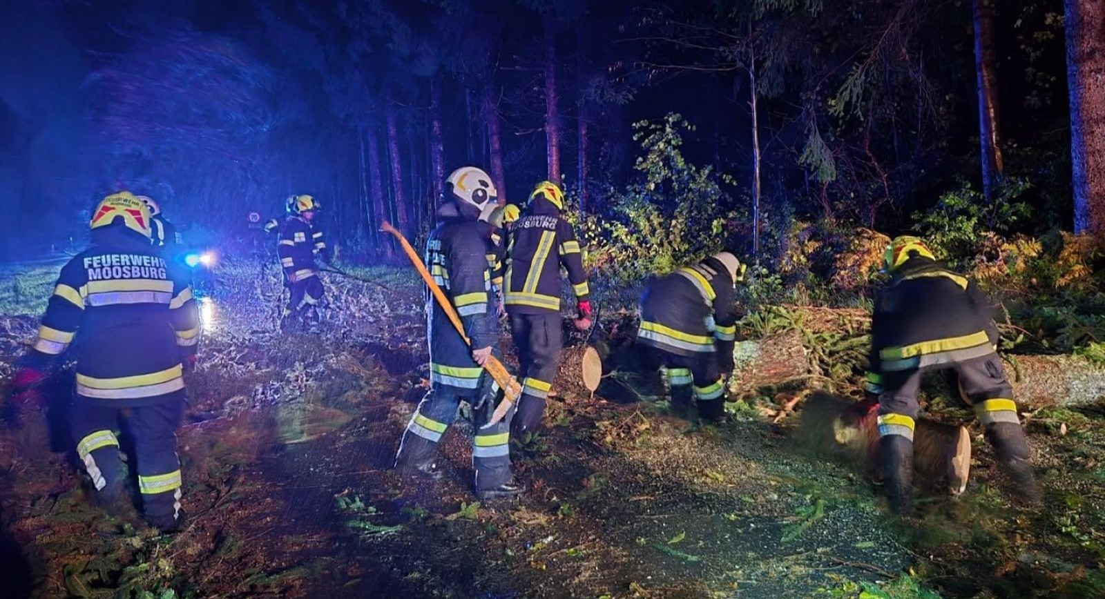 Feuerwehrleute der FF Moosburg räumen in der Nacht nach einem Sturm umgestürzte Bäume von einer Straße in Kärnten.