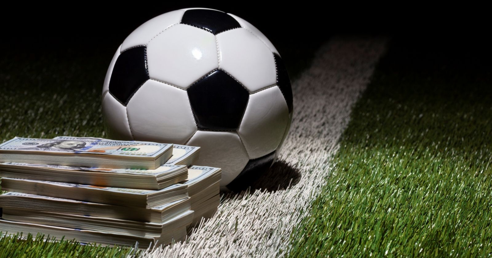 Fußball auf Rasenplatz mit Streifen durch Stapel von Hundert-Dollar-Scheinen