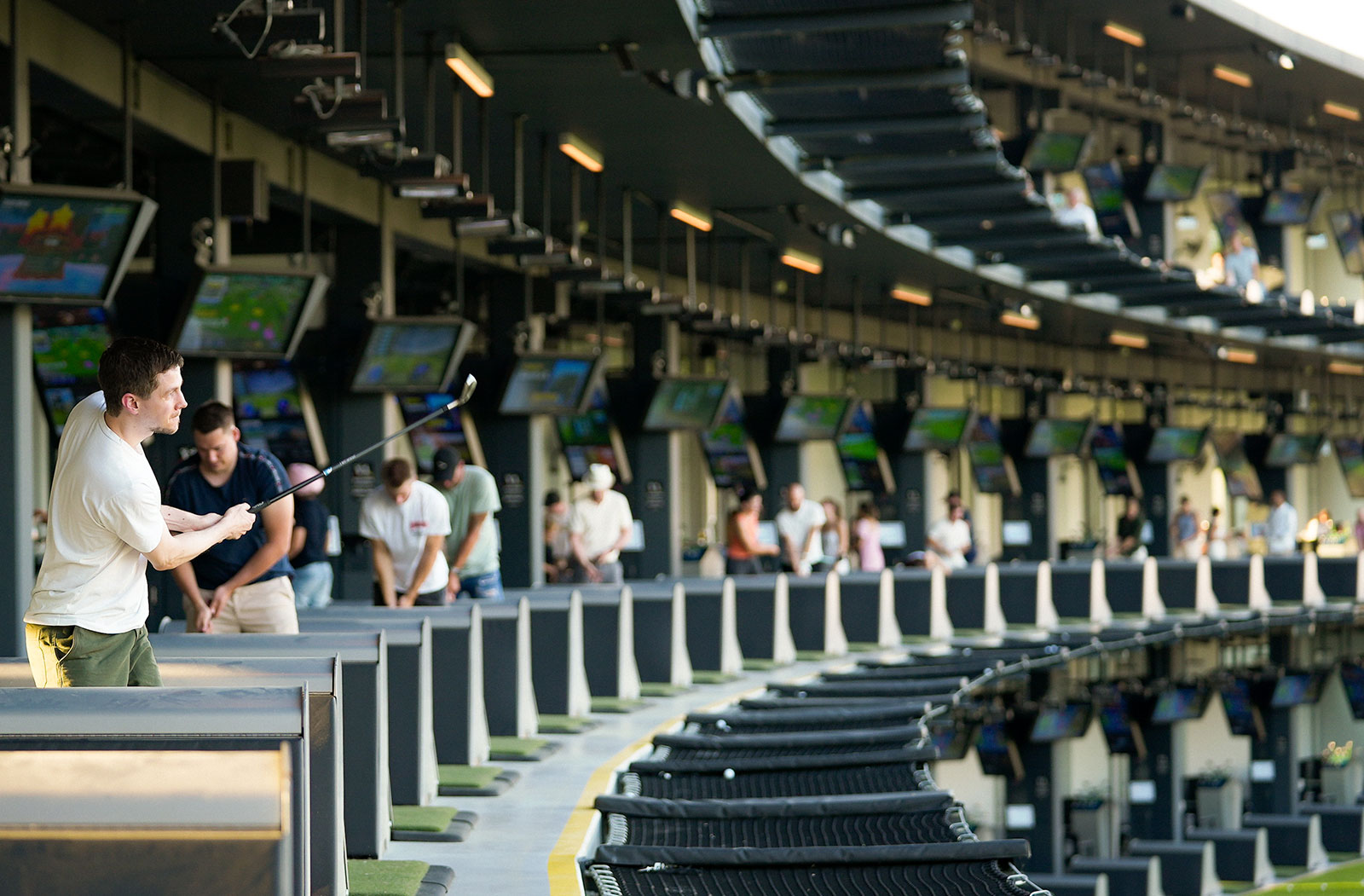 Junger Mann bei Abschlag in einer überdachten Golf-Anlage | Credit: Topgolf Wien