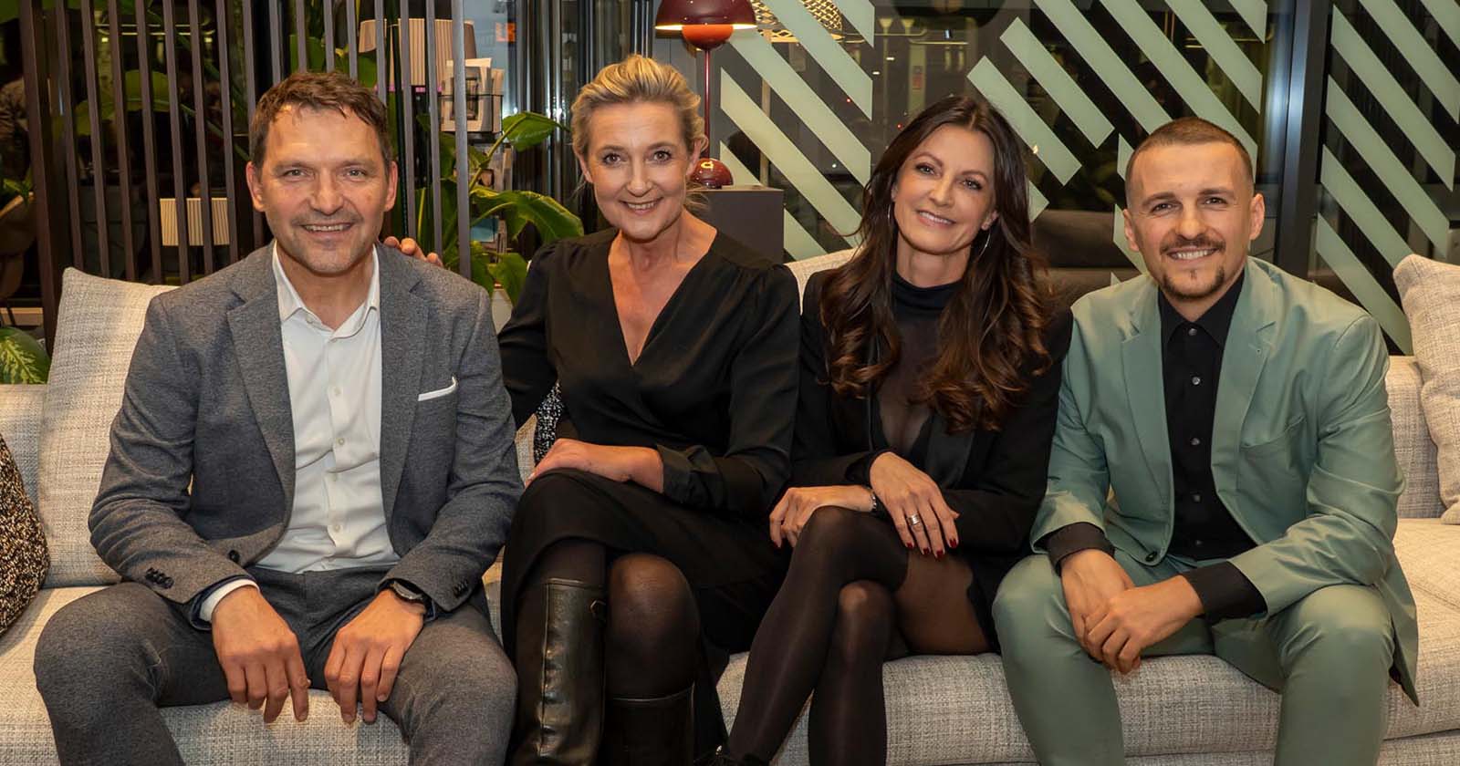 Vier Menschen, die auf einer Couch sitzen und in die Kamera lachen